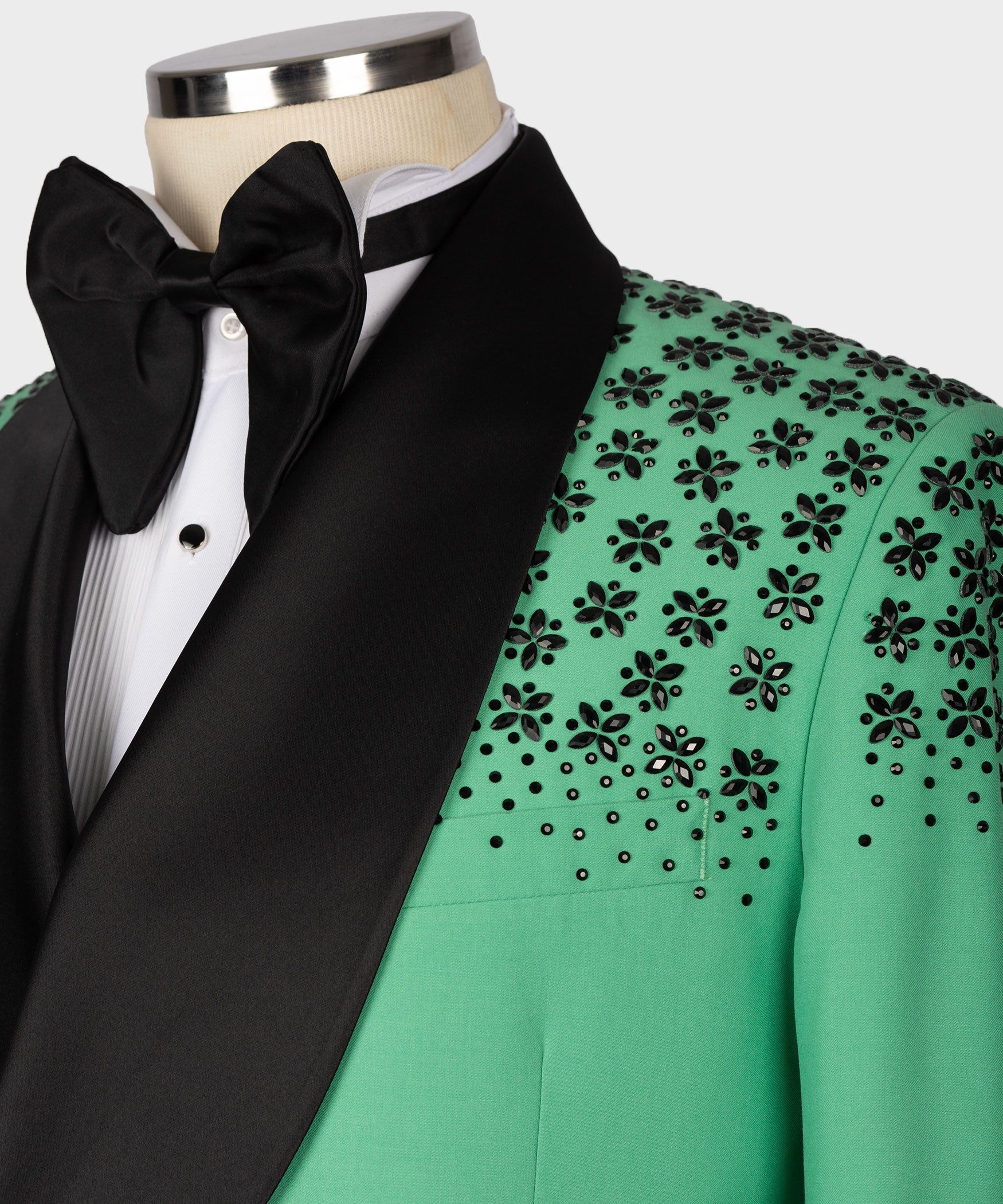 Black bow tie and white shirt under light green tuxedo jacket with stone floral embroidery.