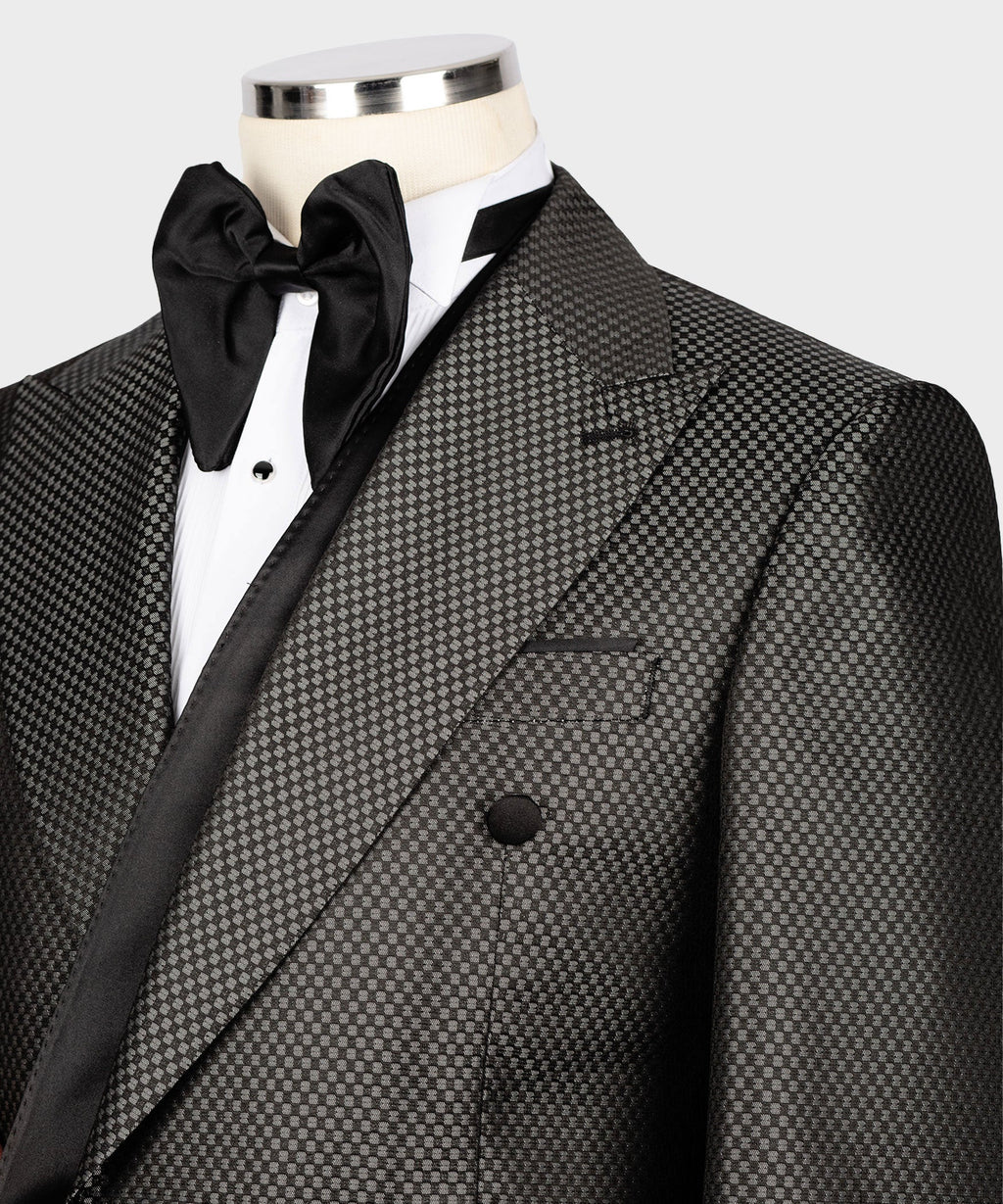Close-up: black satin bow at neck with black buttons on charcoal double-breasted jacket