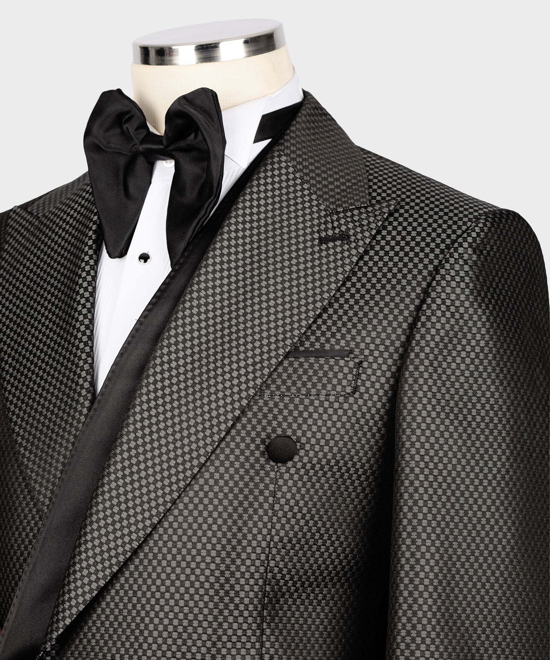 Close-up: black satin bow at neck with black buttons on charcoal double-breasted jacket
