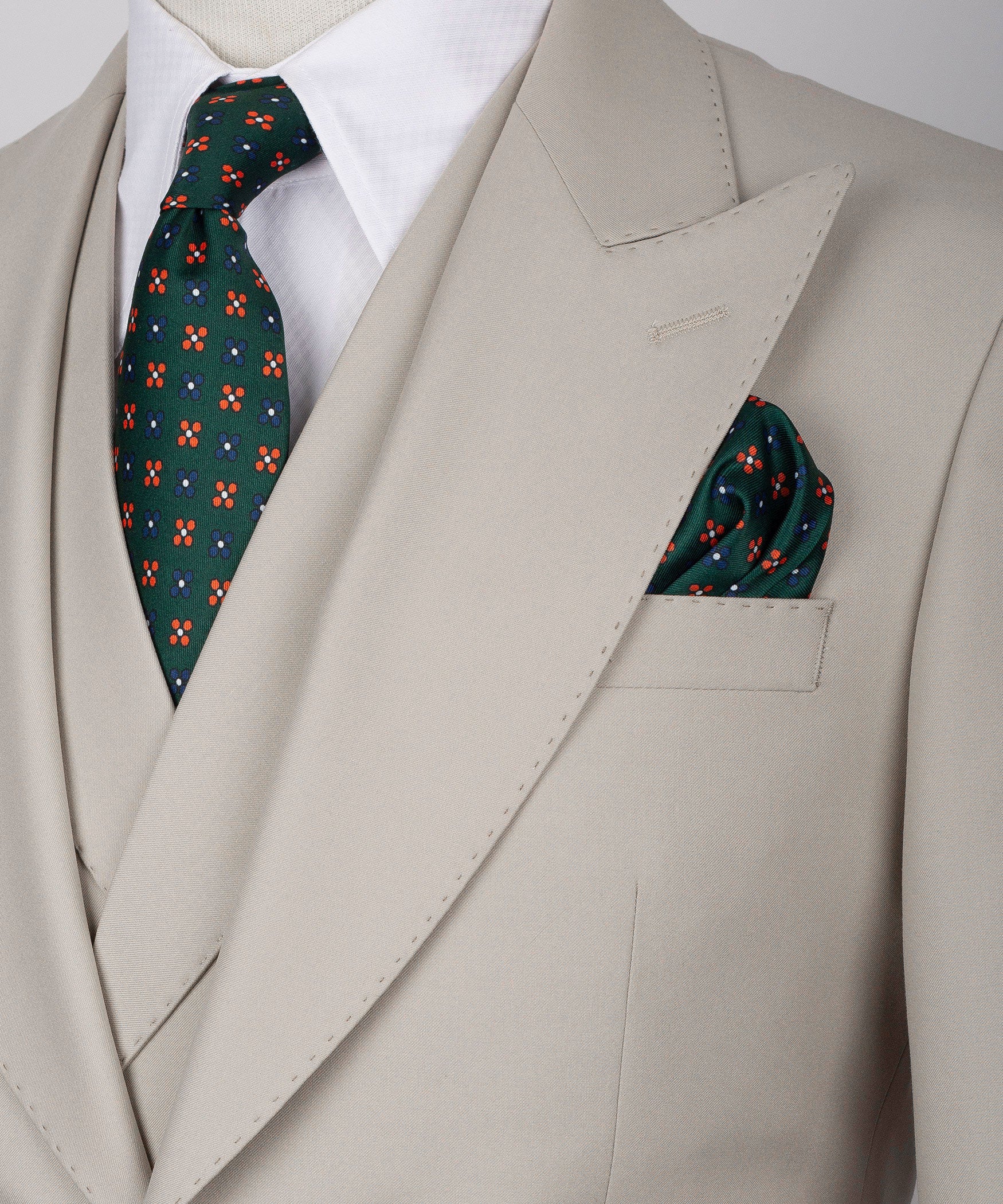 Close-up light taupe lapel with patterned tie and folded pocket square