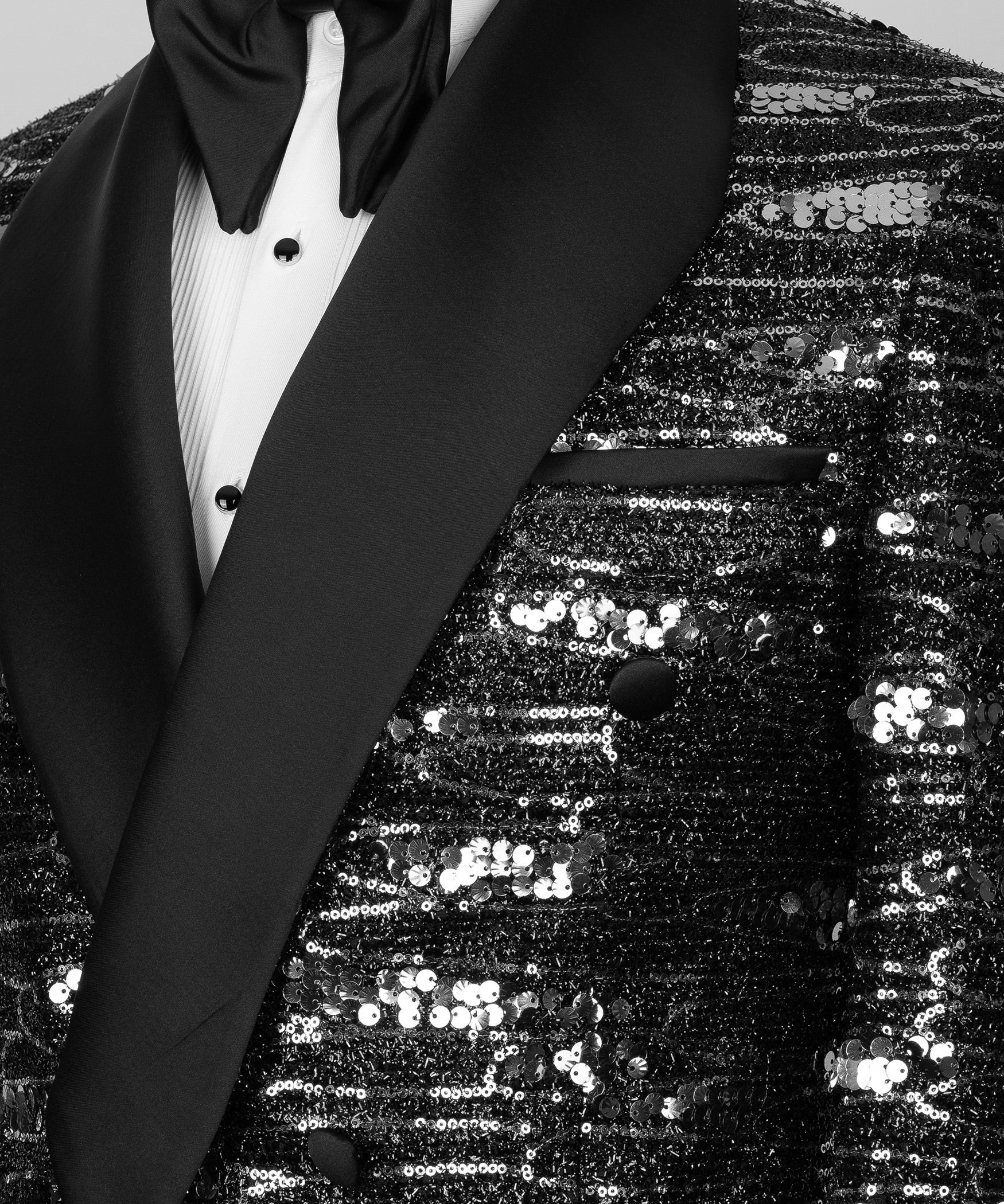 Close-up of black satin shawl lapel and sequined fabric with double-breasted buttons