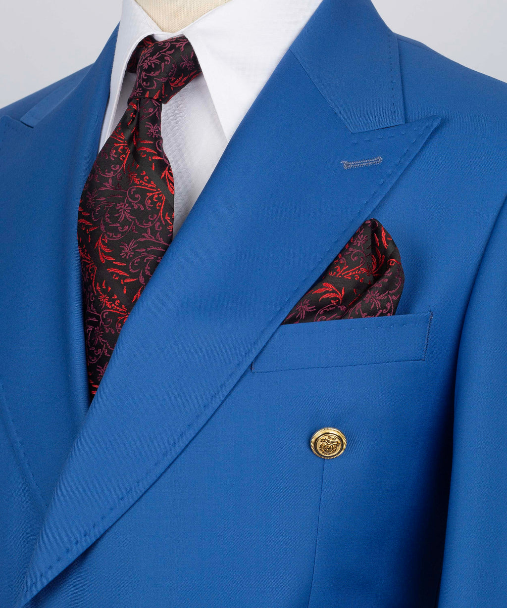 Close-up of blue lapel, gold button, and red patterned pocket square