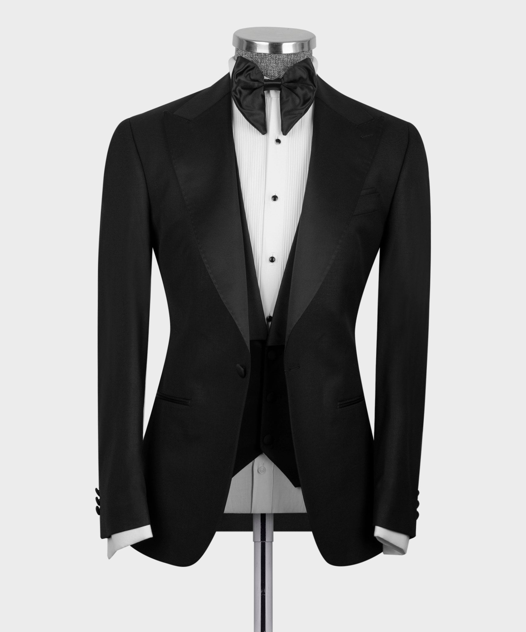 Black tuxedo jacket with satin peak lapels and button vest, bow tie at collar