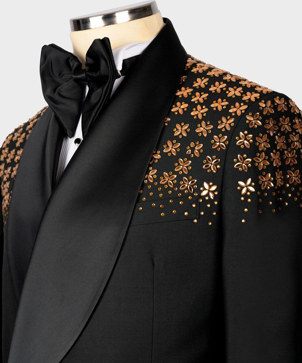 Neckline close-up: black tuxedo jacket with gold floral trim, satin bow, and white shirt.