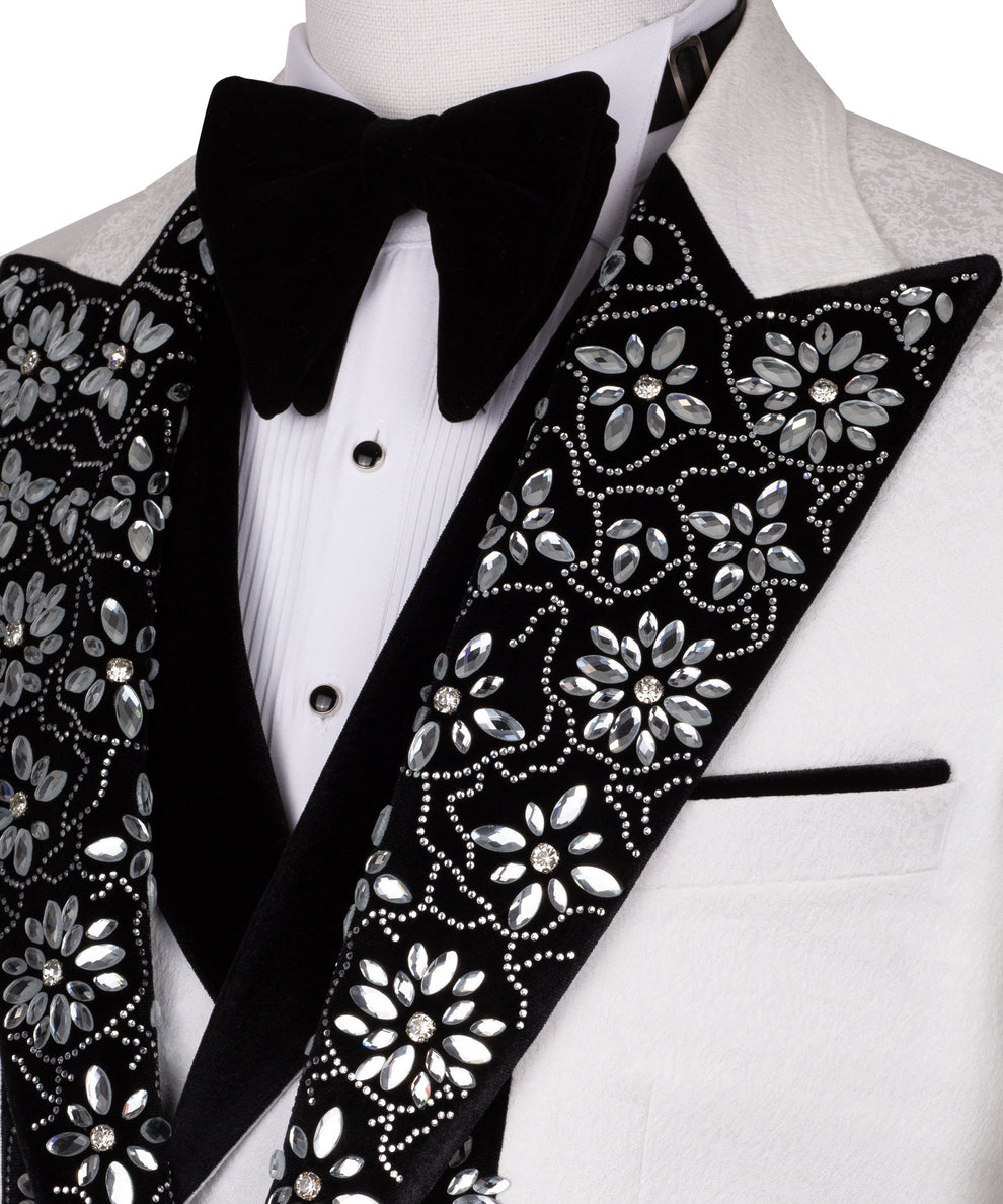 Close-up tuxedo set: black satin bow tie, white shirt buttons, stone-embroidered lapel