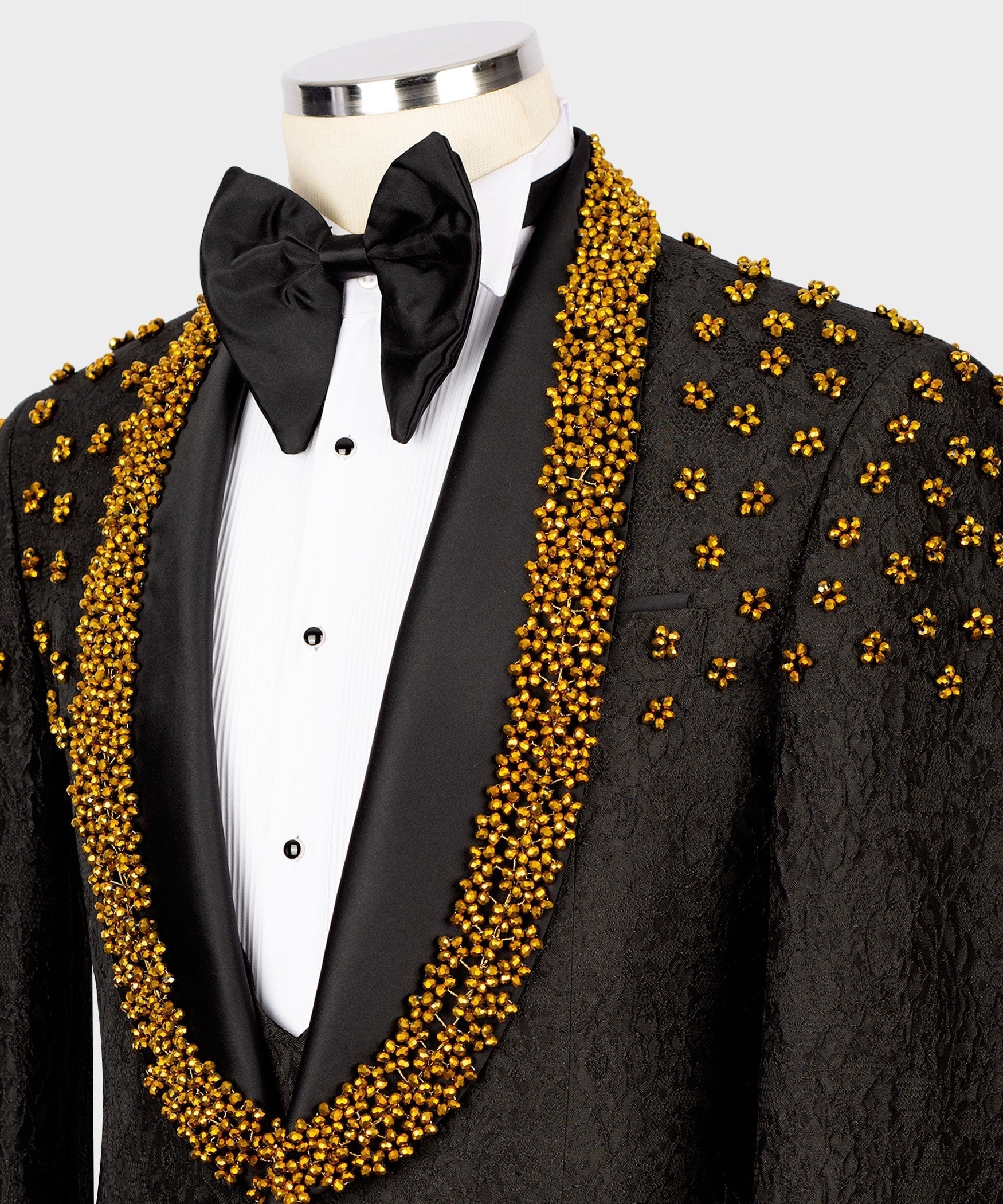 Close-up tuxedo collar: gold bead embroidered lapels and black satin bow tie over white shirt