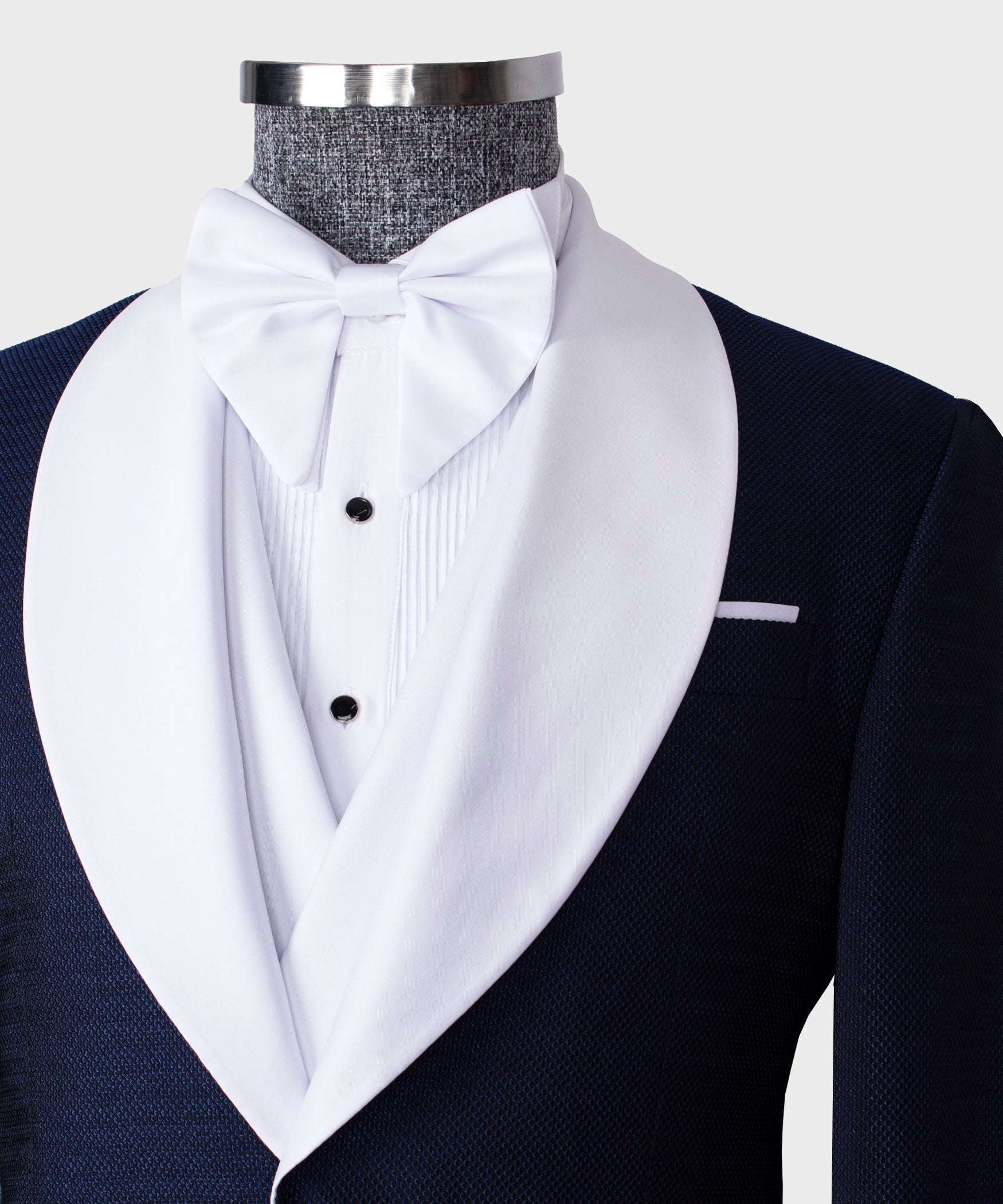 White bow tie and white dress shirt with black buttons under navy tuxedo lapels
