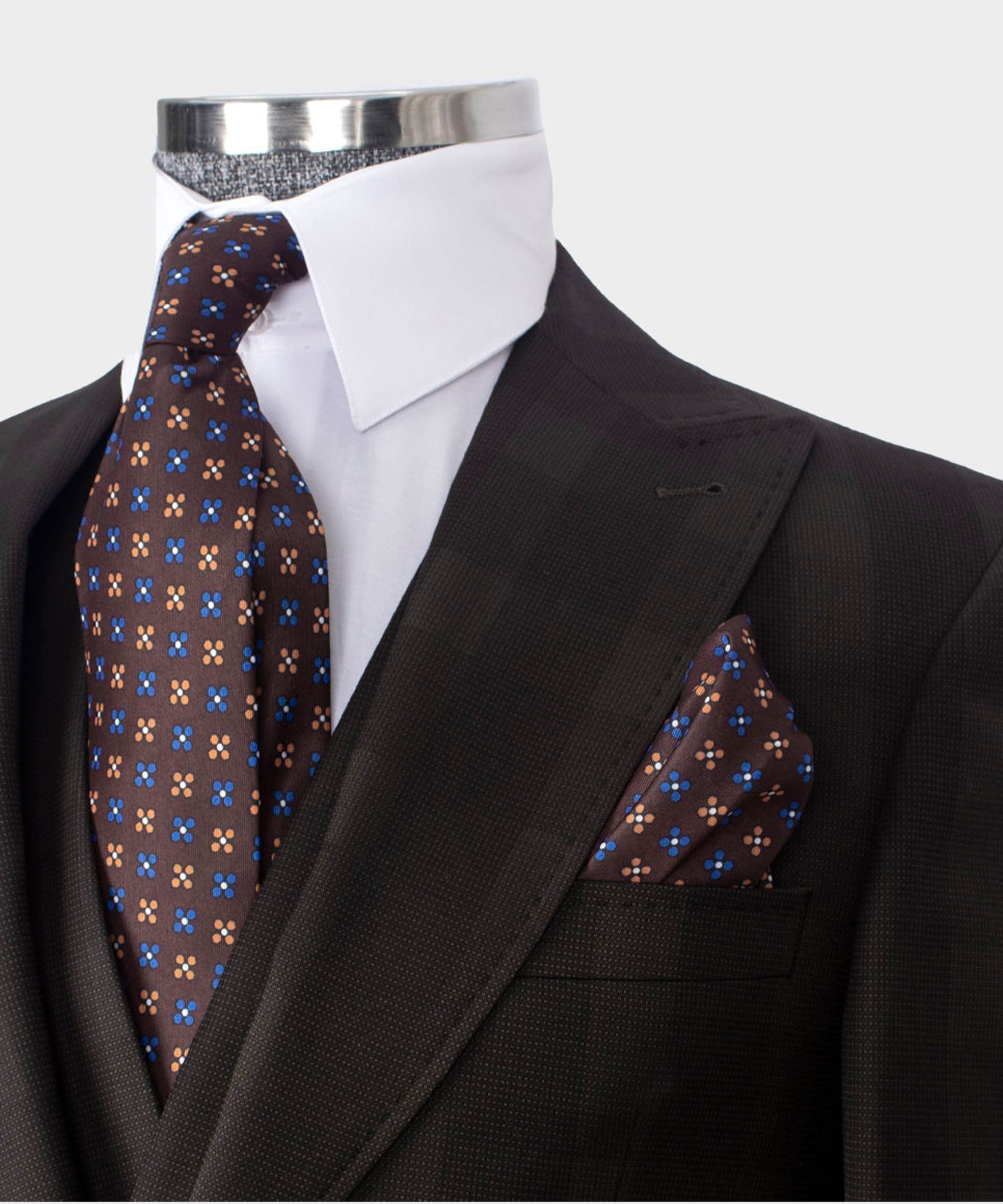 Close-up: dark brown blazer lapel with patterned tie and matching pocket square
