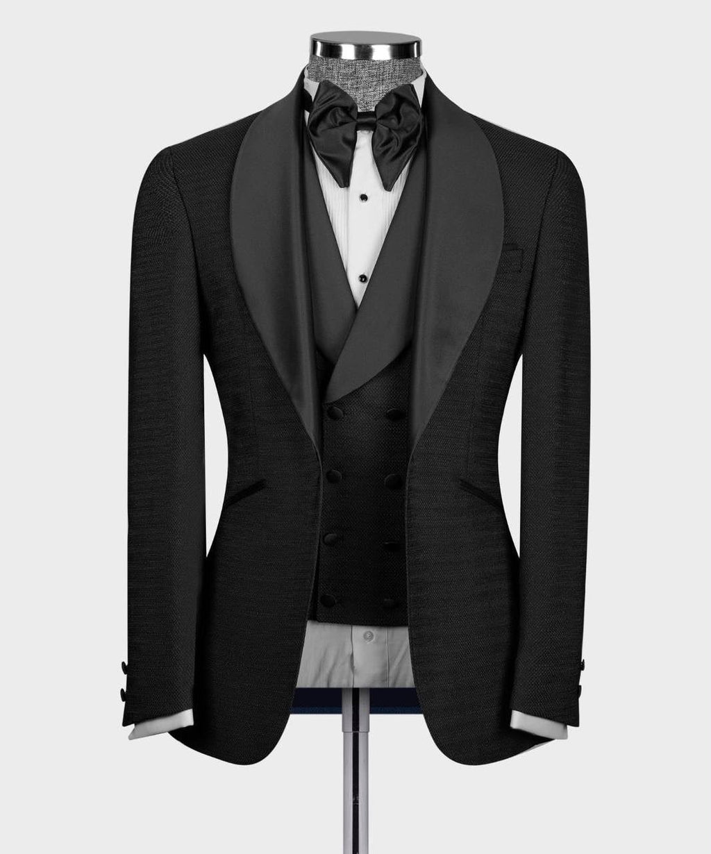A black tuxedo jacket with satin shawl lapels, displayed on a mannequin torso with a black bow tie, white dress shirt, and black vest 