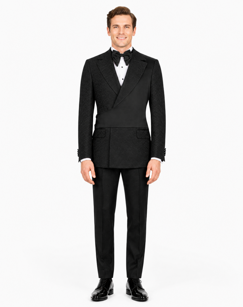 A man modeling a black double-breasted tuxedo with a subtle textured pattern, featuring peak lapels, a white dress shirt, a black bow tie, and black dress shoes, against a plain white background.