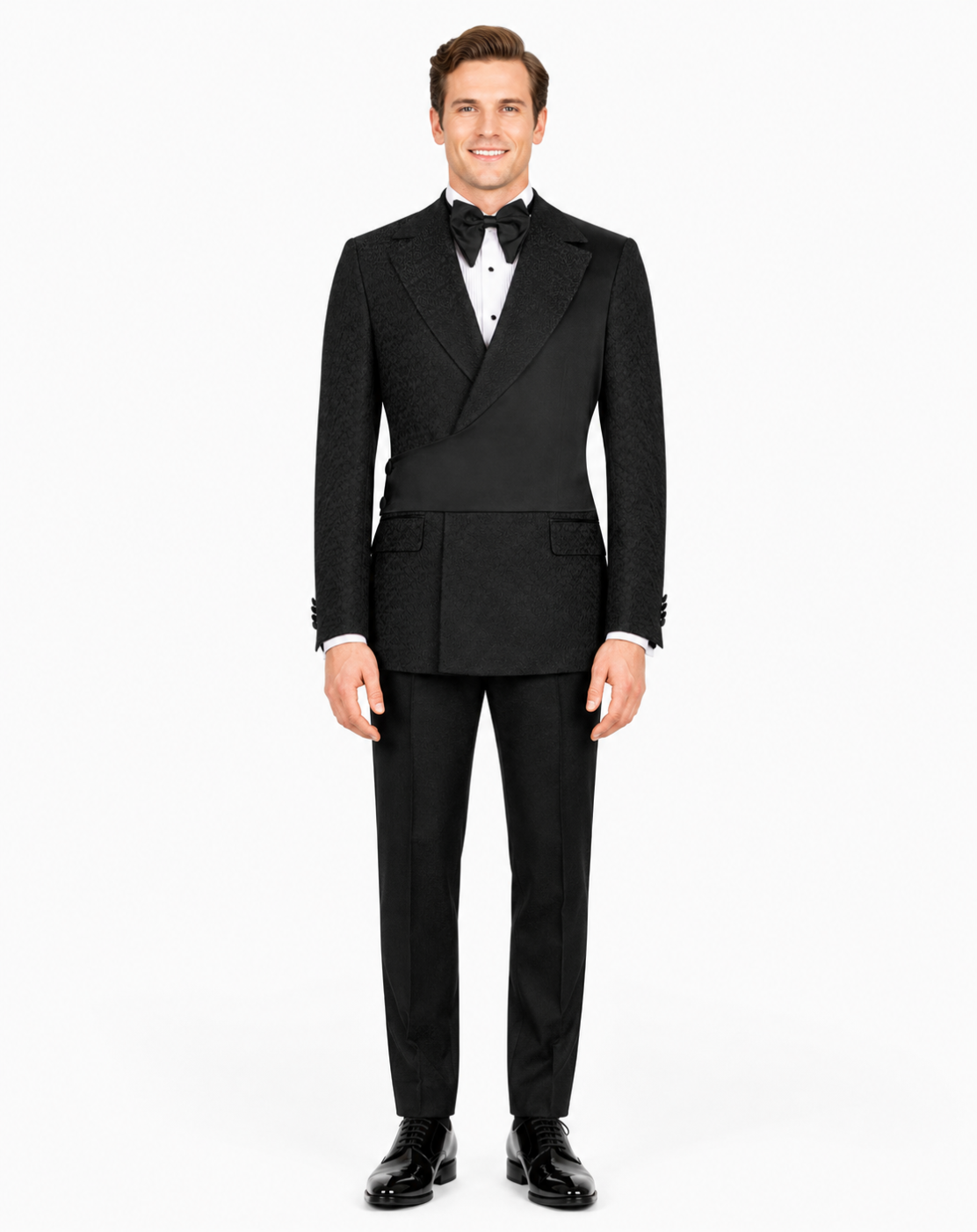 A man modeling a black double-breasted tuxedo with a subtle textured pattern, featuring peak lapels, a white dress shirt, a black bow tie, and black dress shoes, against a plain white background.