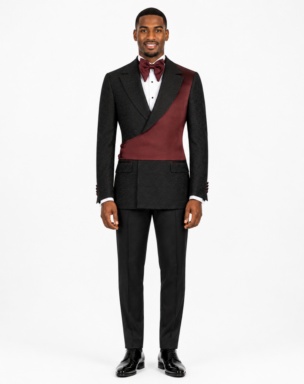 A man modeling a black double-breasted tuxedo with a contrasting burgundy satin peak lapel and matching bow tie