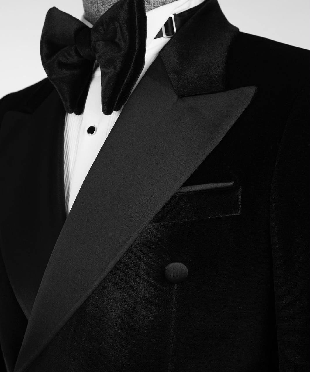 Close-up of a black tuxedo jacket with satin lapels, a matching black bow tie, and a white dress shirt.