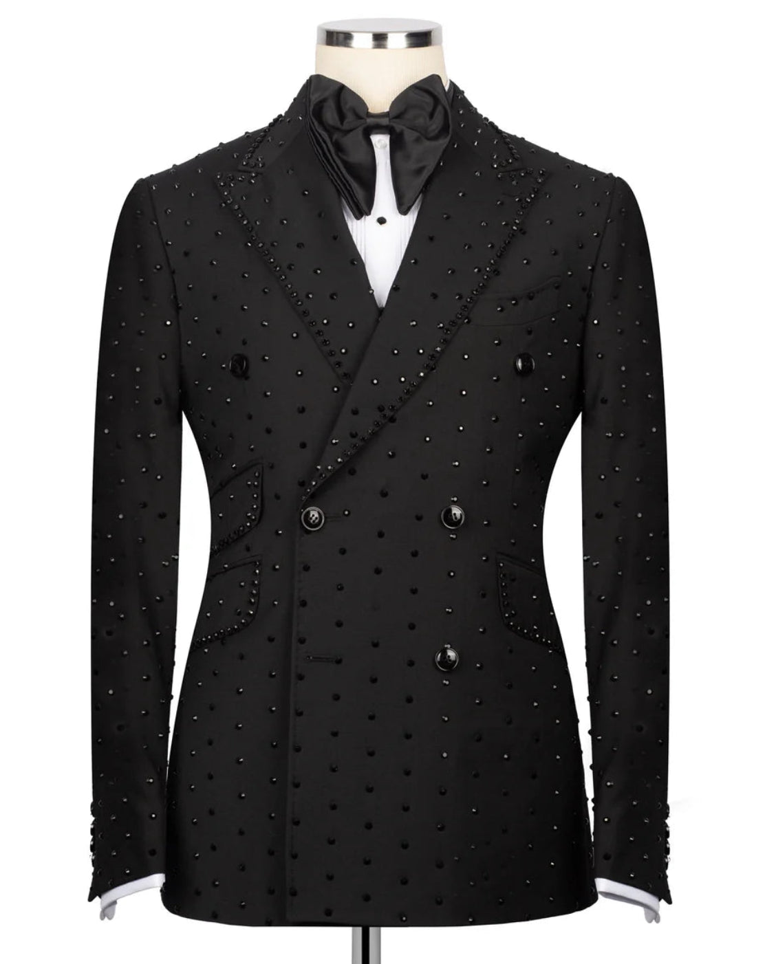 A black double-breasted tuxedo jacket embellished with small silver studs, displayed on a mannequin with a black bow tie and white shirt.