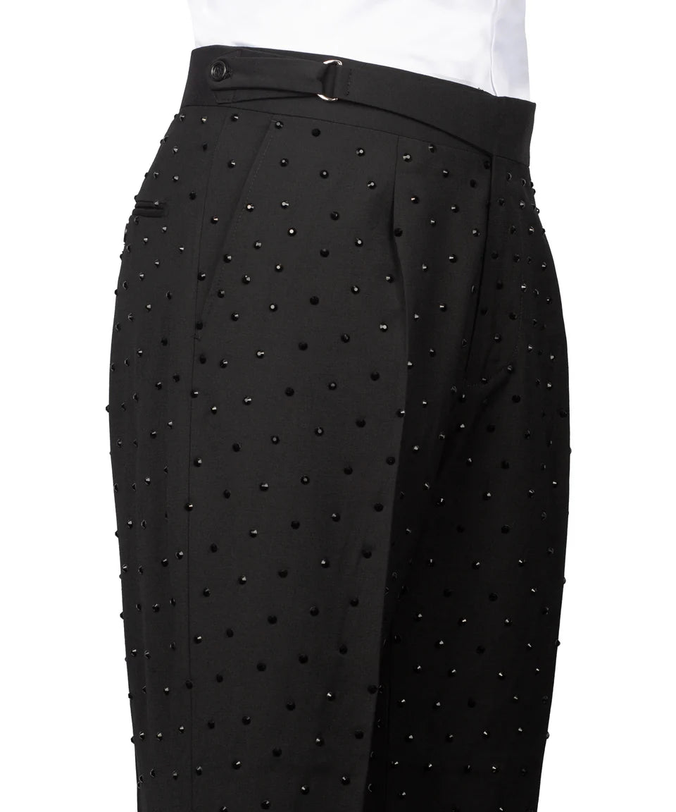 Black trousers with a dotted pattern of small black studs, featuring a matching black belt and a white shirt hem visible at the top, shot against a white background.