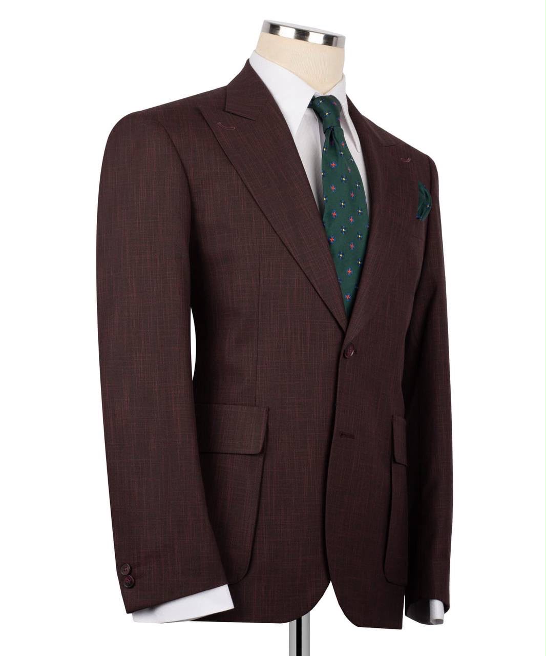 A dark brown textured suit jacket displayed on a mannequin torso, styled with a white dress shirt, a green patterned tie, and a matching pocket square against a plain white background.