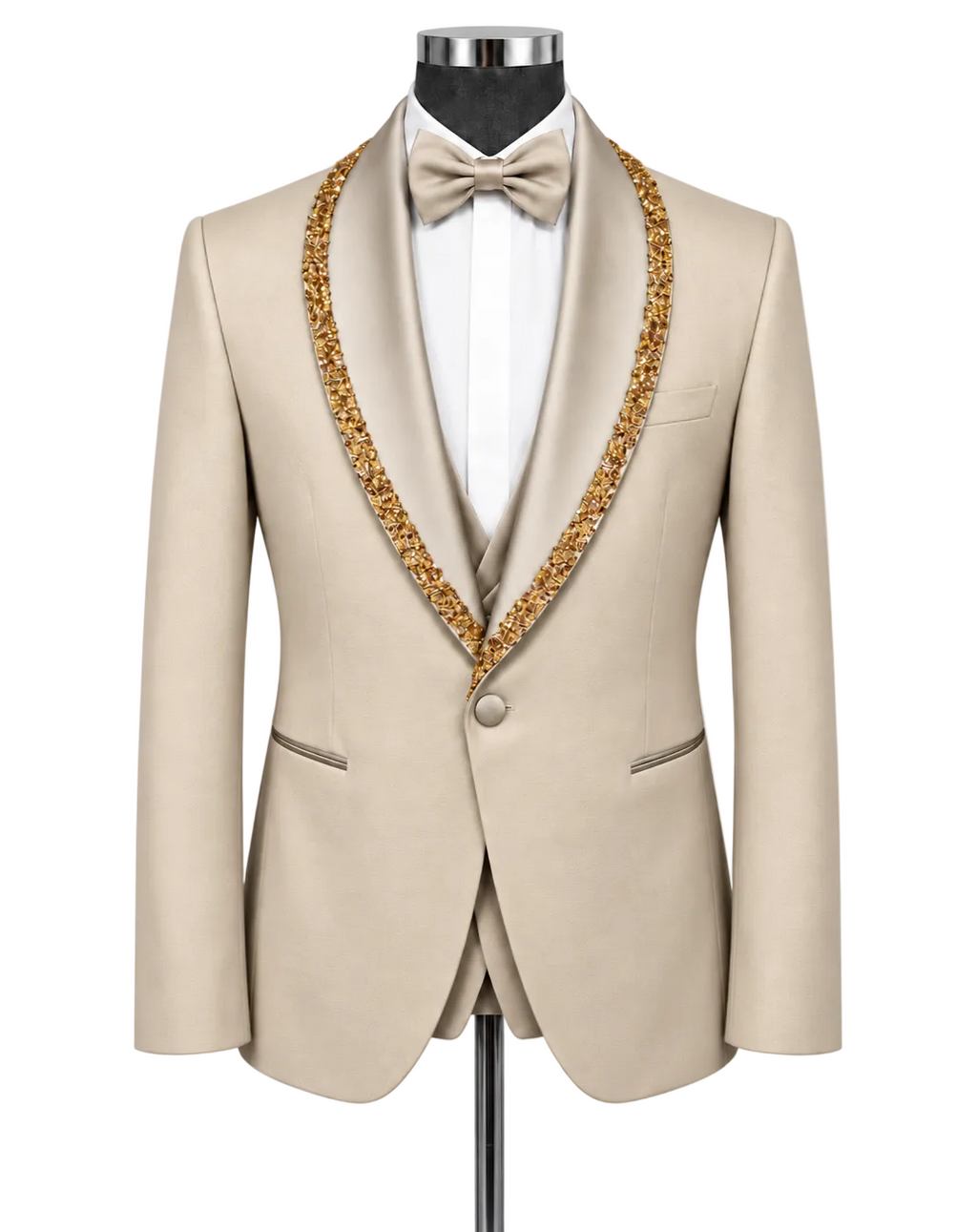 A beige tuxedo jacket with ornate gold beaded trim along the shawl collar, displayed on a mannequin with a white dress shirt, white bow tie, and matching beige vest.