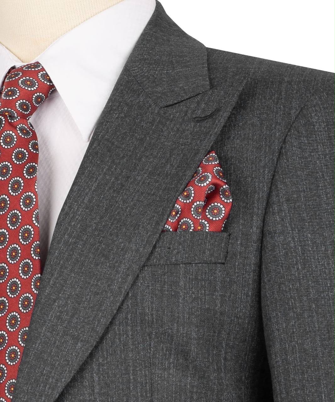 A close-up of a dark gray textured suit jacket styled with a white dress shirt, a red patterned tie, and a matching red patterned pocket square.