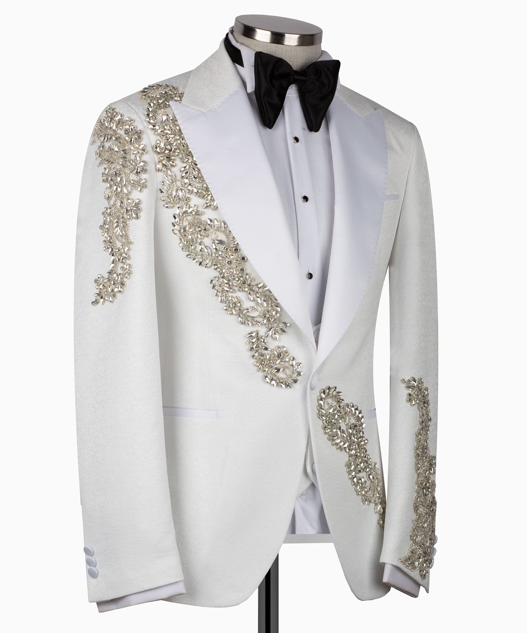 White tuxedo suit with gold stone-embellished lapel and pocket trim, black bow tie