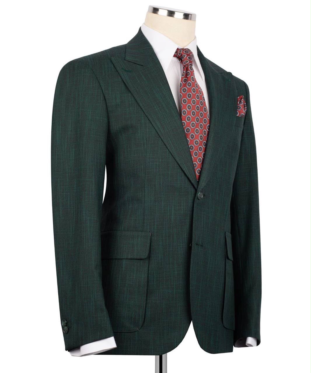 A dark green plaid suit jacket displayed on a mannequin torso, styled with a white dress shirt and a red patterned tie.
