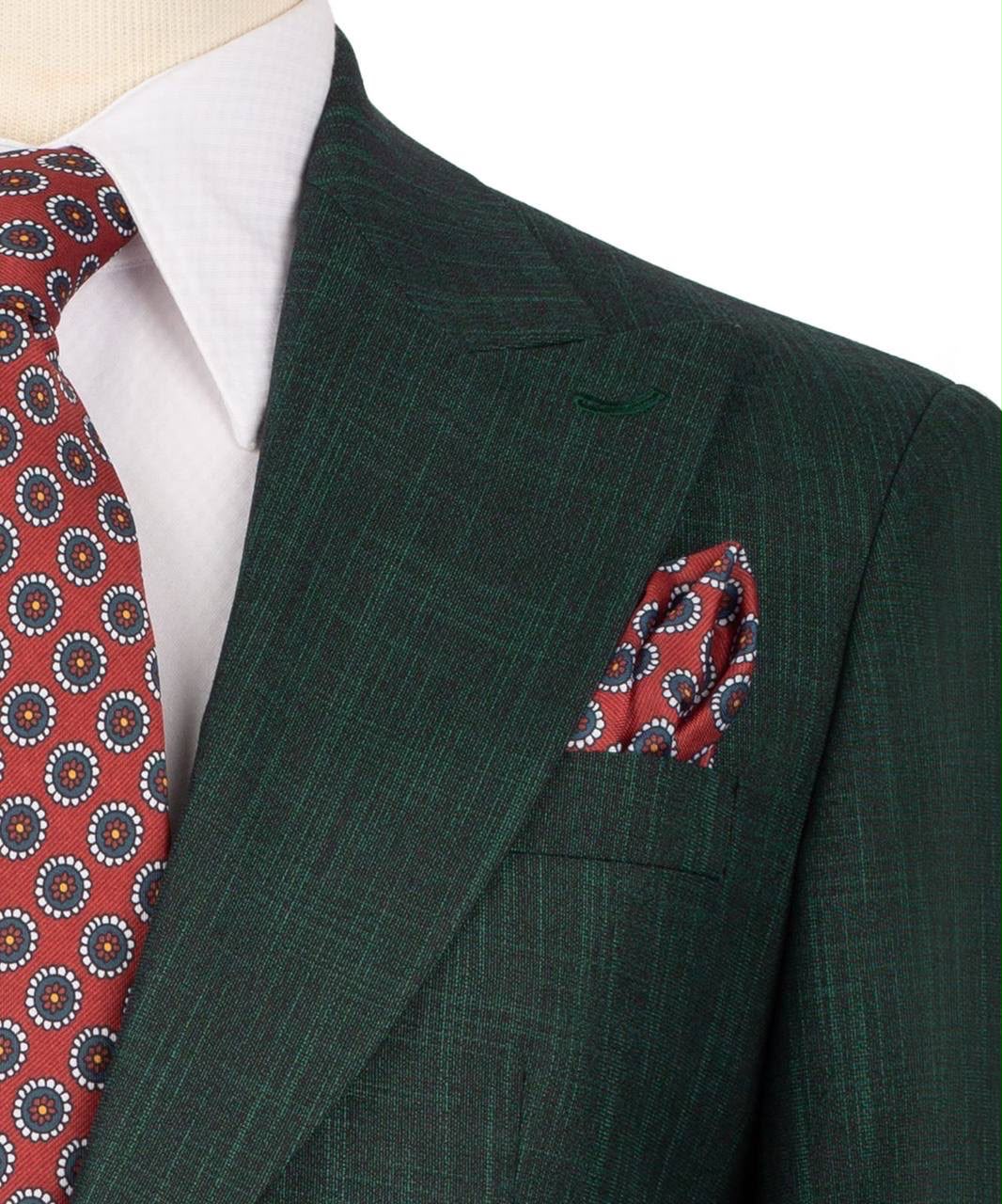 A close-up of a dark green suit jacket with a subtle windowpane pattern, styled with a red patterned tie and matching pocket square over a white dress shirt.