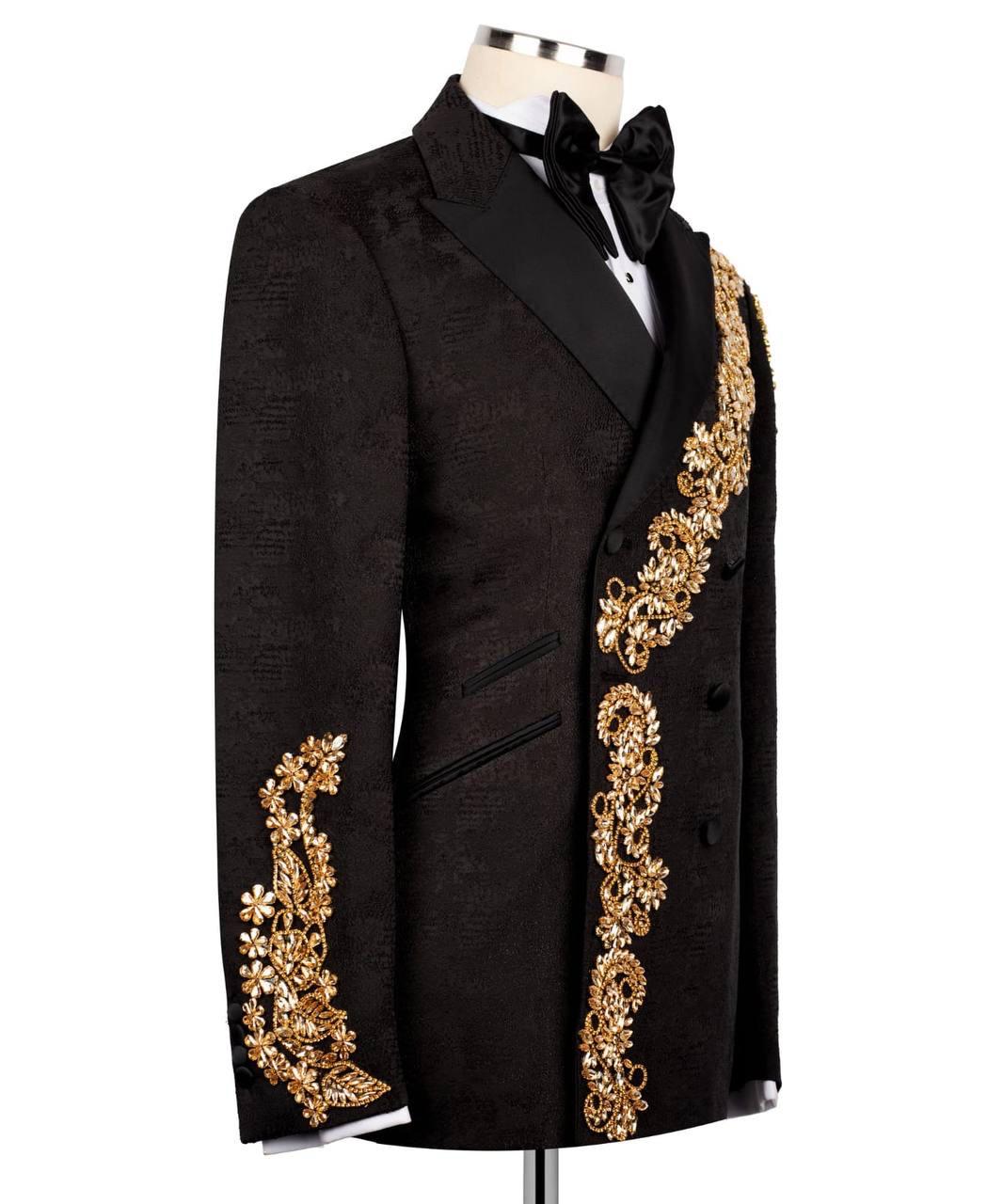 A black double-breasted tuxedo jacket with ornate gold floral embroidery on the lapels and sleeves, displayed on a mannequin with a black bow tie and white shirt