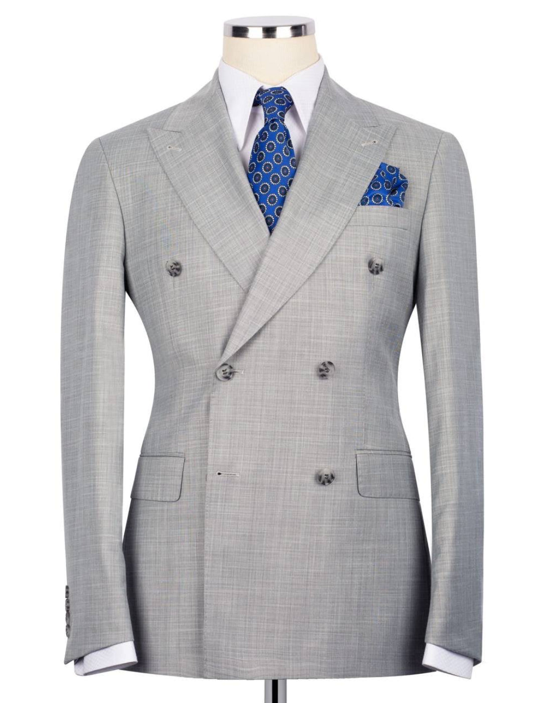 A light gray double-breasted suit jacket with a subtle micro-check pattern, displayed on a mannequin torso with a white dress shirt, blue patterned tie, and matching pocket square.