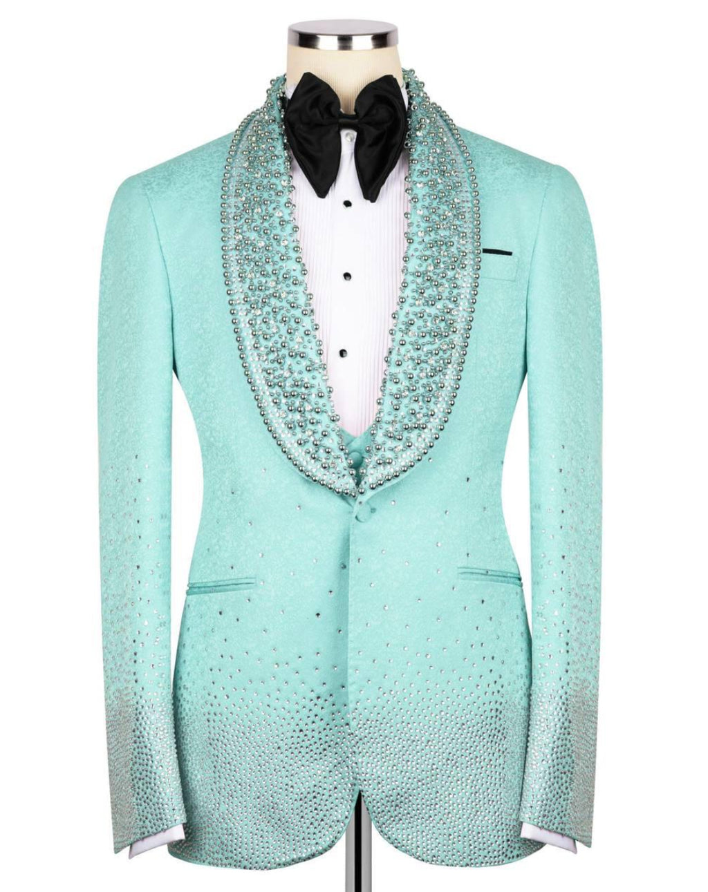A mint green tuxedo jacket with sparkling rhinestone embellishments, styled on a mannequin with a white shirt, black bow tie, and a matching rhinestone-trimmed collar.