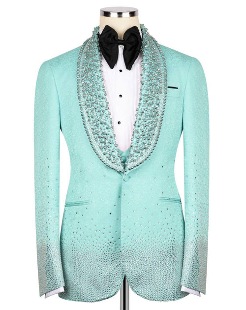 A mint green tuxedo jacket with sparkling rhinestone embellishments, styled on a mannequin with a white shirt, black bow tie, and a matching rhinestone-trimmed collar.