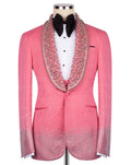 A pink tuxedo jacket embellished with sparkling rhinestones, featuring a wide collar lined with dense rhinestone detailing, displayed on a mannequin with a white shirt and black bow tie.