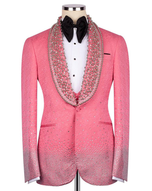 A pink tuxedo jacket embellished with sparkling rhinestones, featuring a wide collar lined with dense rhinestone detailing, displayed on a mannequin with a white shirt and black bow tie.