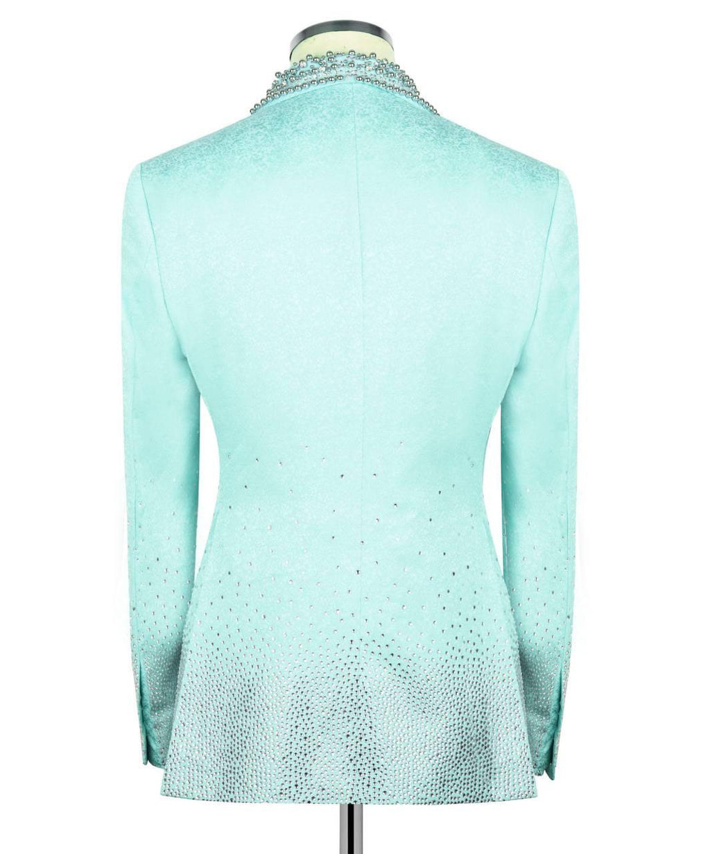 A light aqua blue long-sleeve blazer jacket with a textured, glittery finish, shown from the back on a mannequin. The jacket features a subtle gradient effect with denser rhinestone-like embellishments concentrated near the collar and the lower hem.