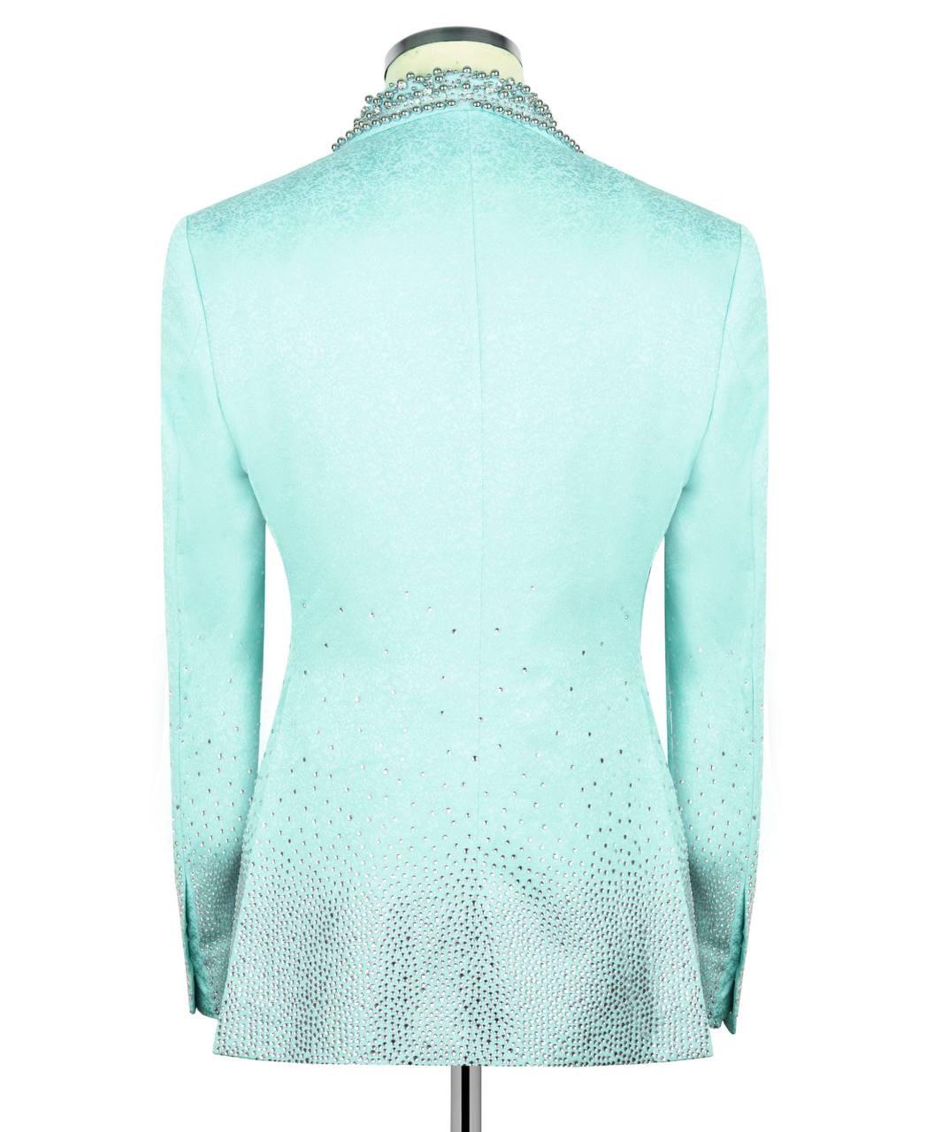A light aqua blue long-sleeve blazer jacket with a textured, glittery finish, shown from the back on a mannequin. The jacket features a subtle gradient effect with denser rhinestone-like embellishments concentrated near the collar and the lower hem.