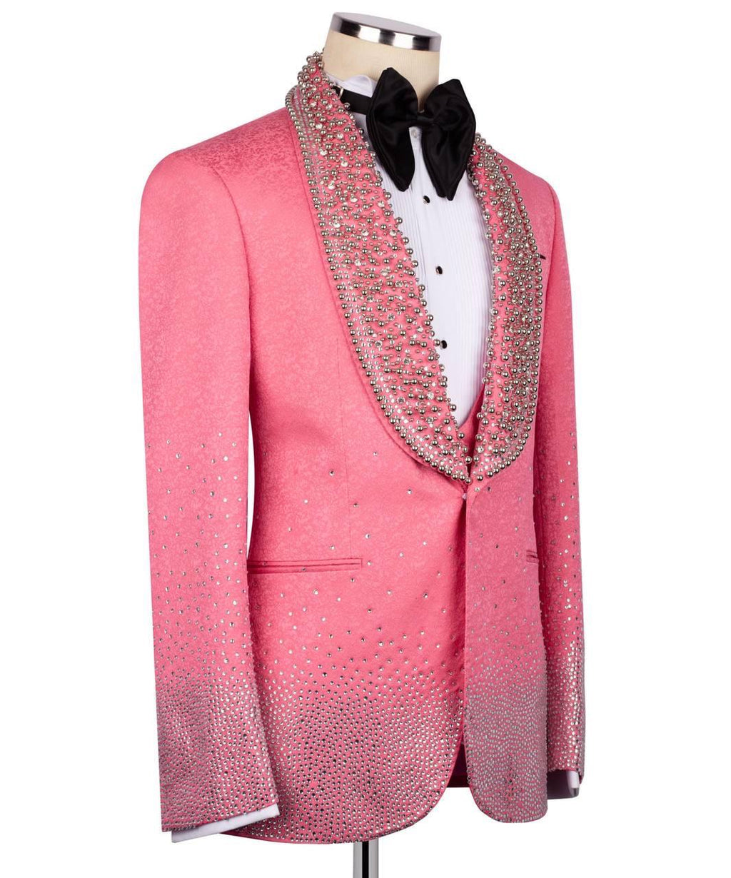 A pink tuxedo jacket with a gradient rhinestone and crystal embellishment pattern, styled on a mannequin with a white shirt, black bow tie, and a matching crystal-trimmed collar.