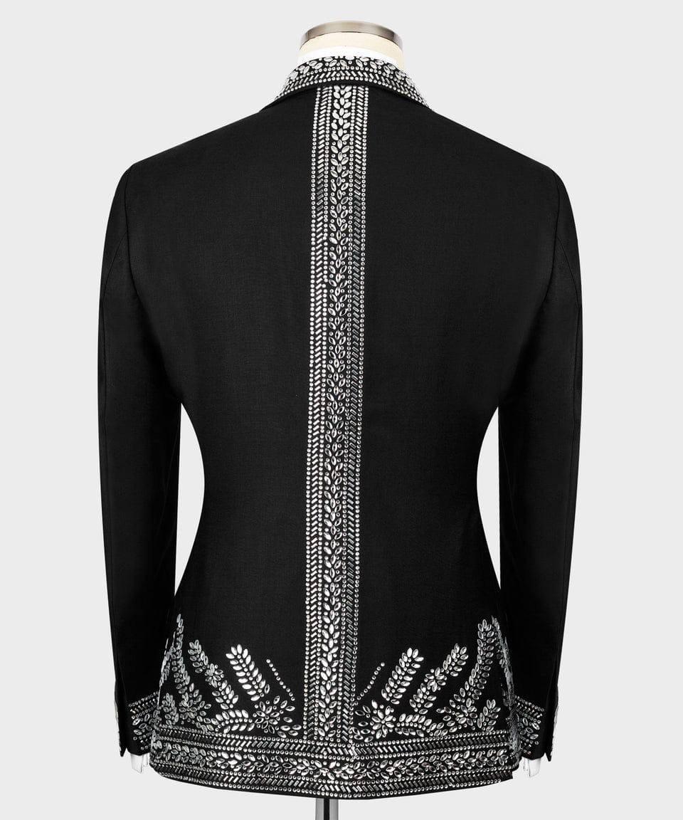 Black long-sleeve jacket shown from the back on a mannequin, featuring ornate silver-toned embroidery running down the center back and along the hem.