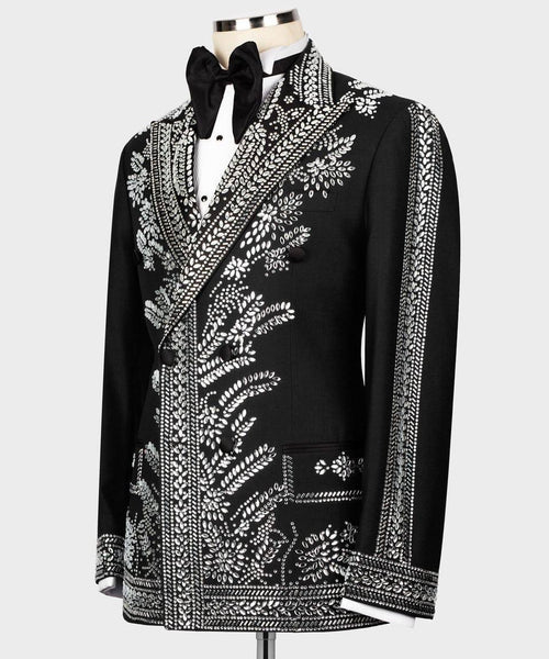 A black men's tuxedo jacket with elaborate silver beaded floral and geometric embroidery, styled on a mannequin with a black bow tie and white shirt against a light gray background.