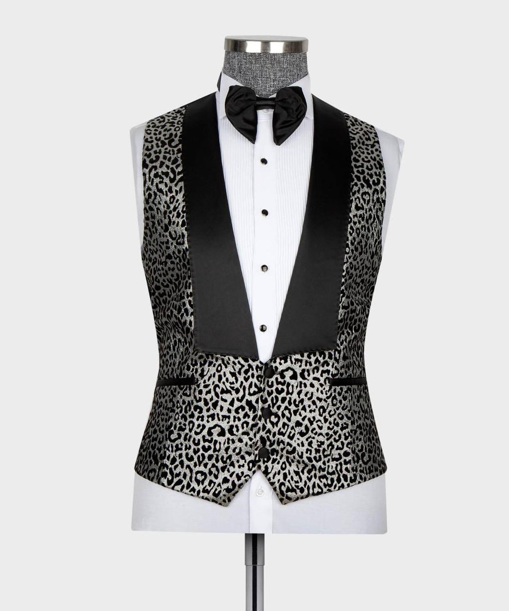 A men's tuxedo vest with a black and gray leopard print pattern and black satin peak lapels, displayed on a white dress shirt and black bow tie mannequin against a light gray background.