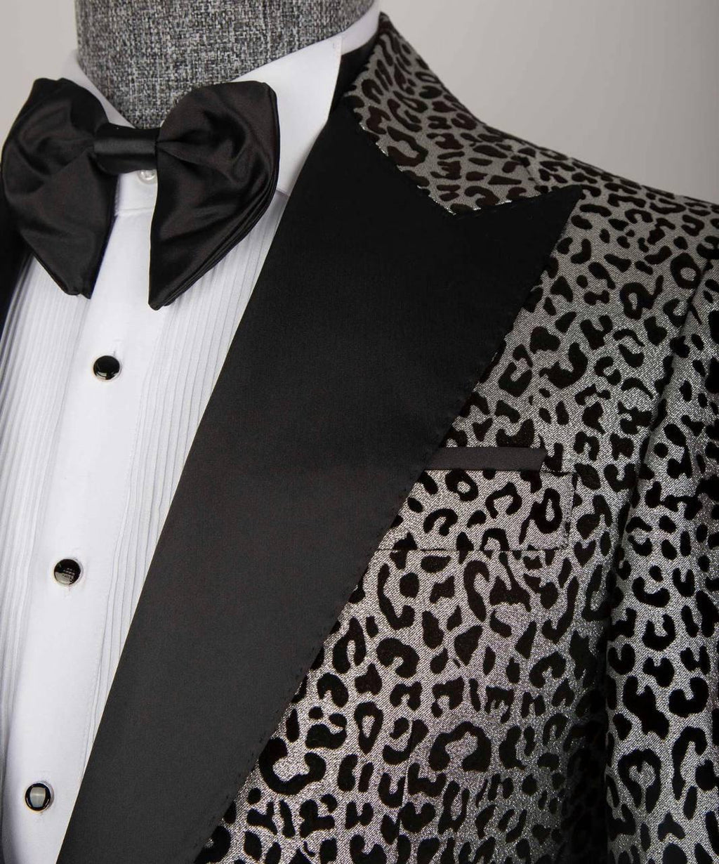 A close-up of a men's tuxedo jacket featuring a black and gray leopard print pattern on the body and lapels, paired with solid black satin peak lapels, a white pleated shirt, and a black bow tie.