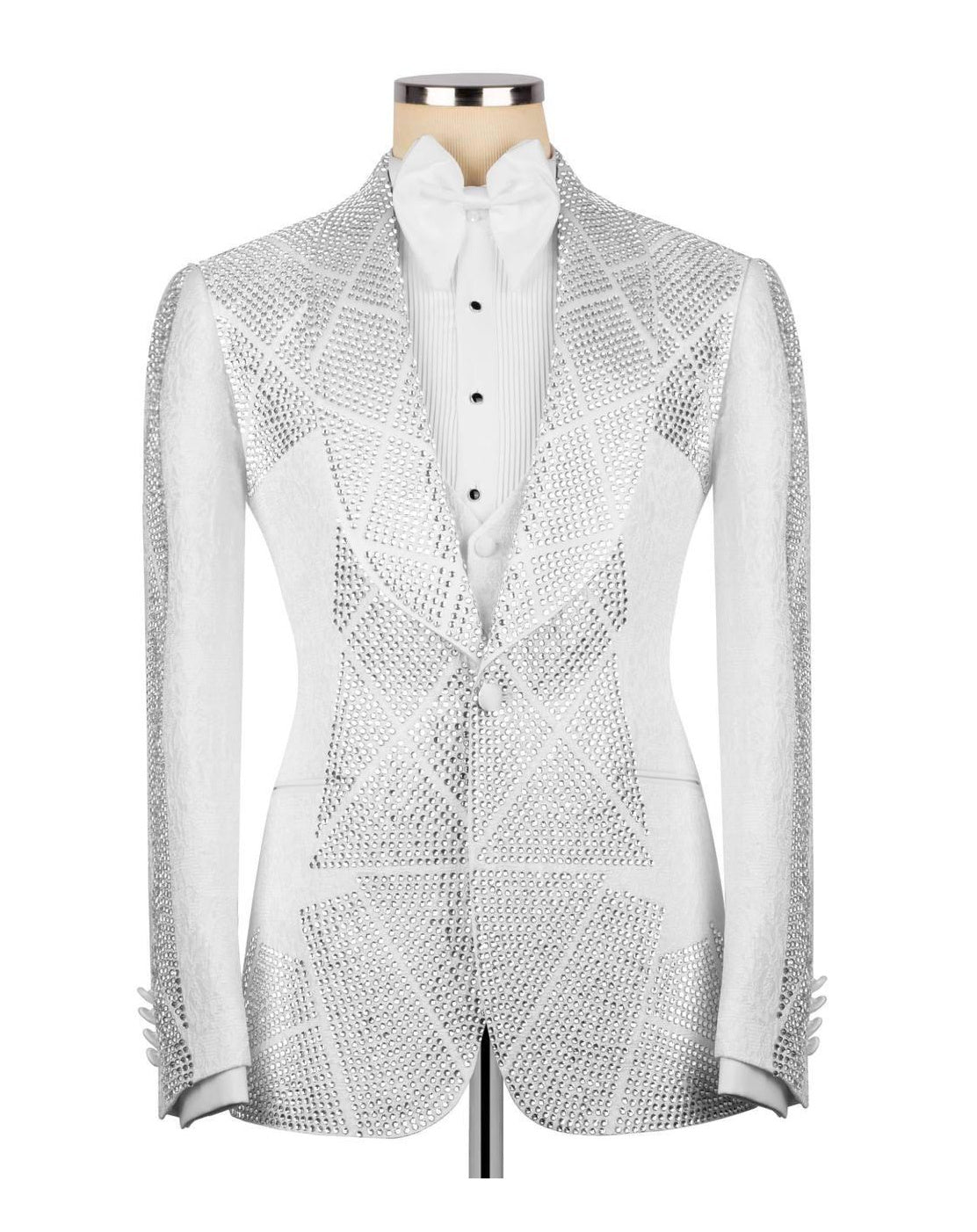 A white tuxedo jacket embellished with intricate silver rhinestone geometric patterns, displayed on a mannequin torso with a white pleated shirt and bow tie.