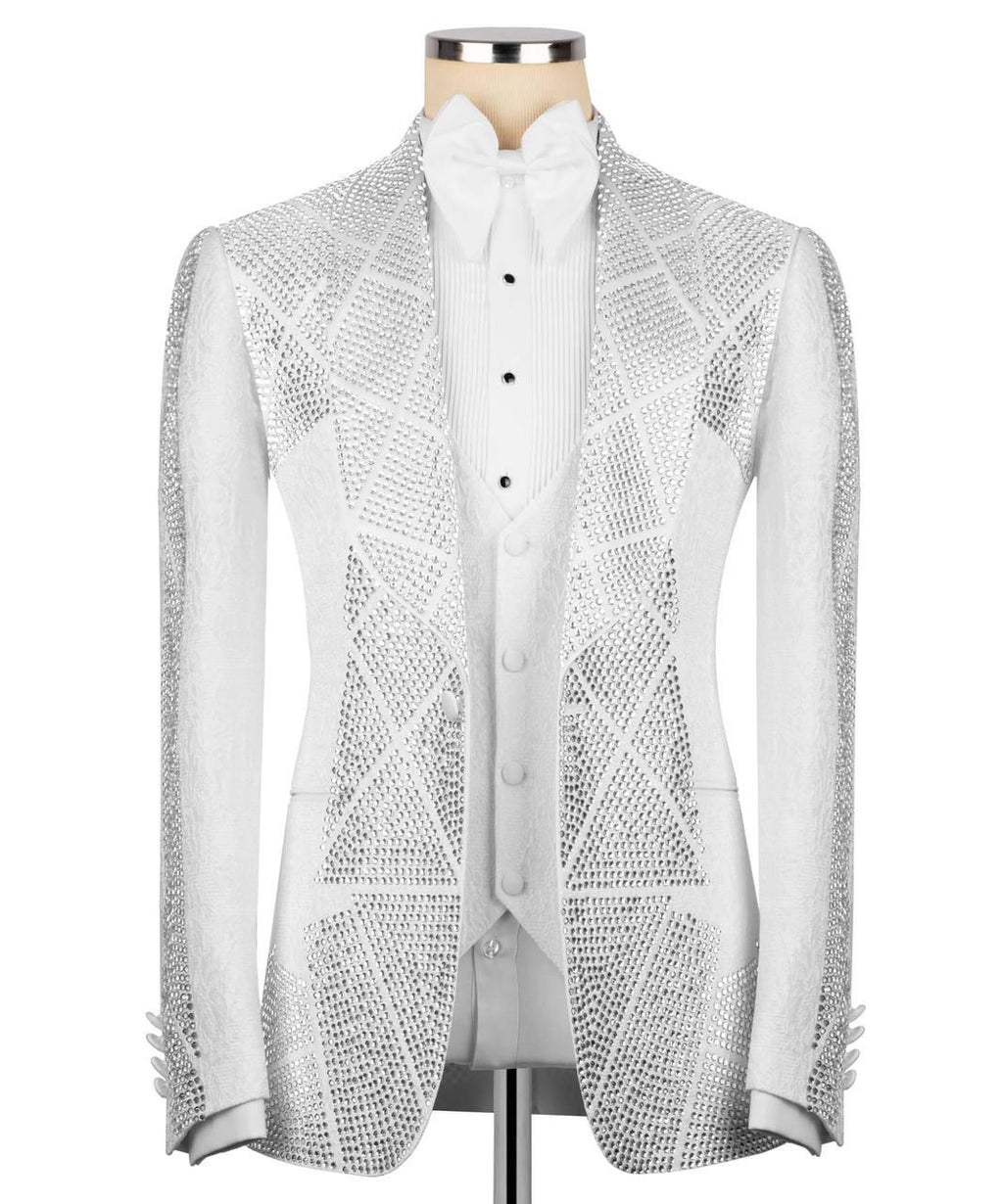 A white tuxedo jacket embellished with intricate silver rhinestone geometric patterns, displayed on a mannequin torso with a matching white pleated vest and bow tie.