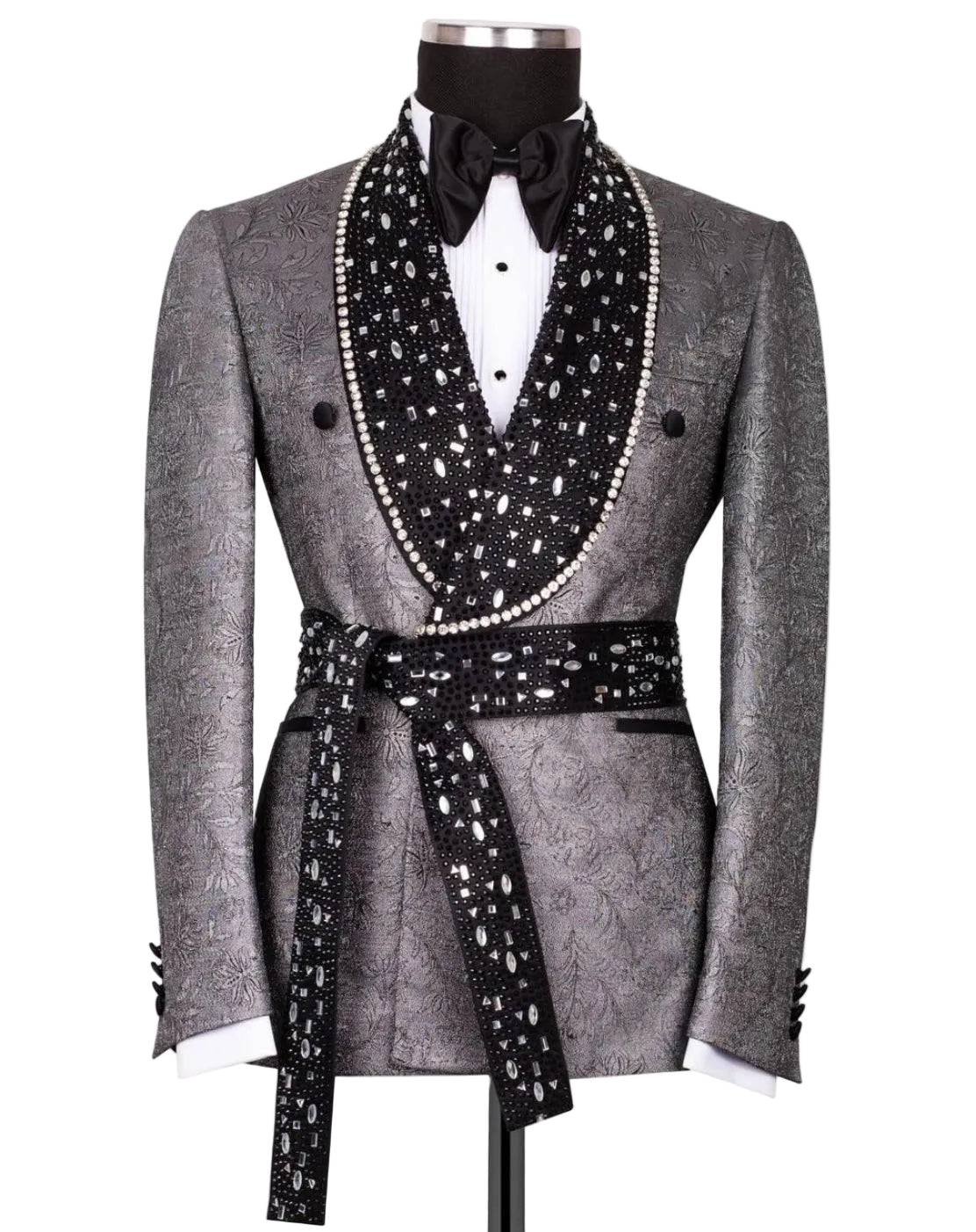 A men's tuxedo jacket displayed on a mannequin, featuring a textured gray patterned body with a wide black shawl collar and matching waist tie adorned with white rhinestones, styled with a white shirt and black bow tie.