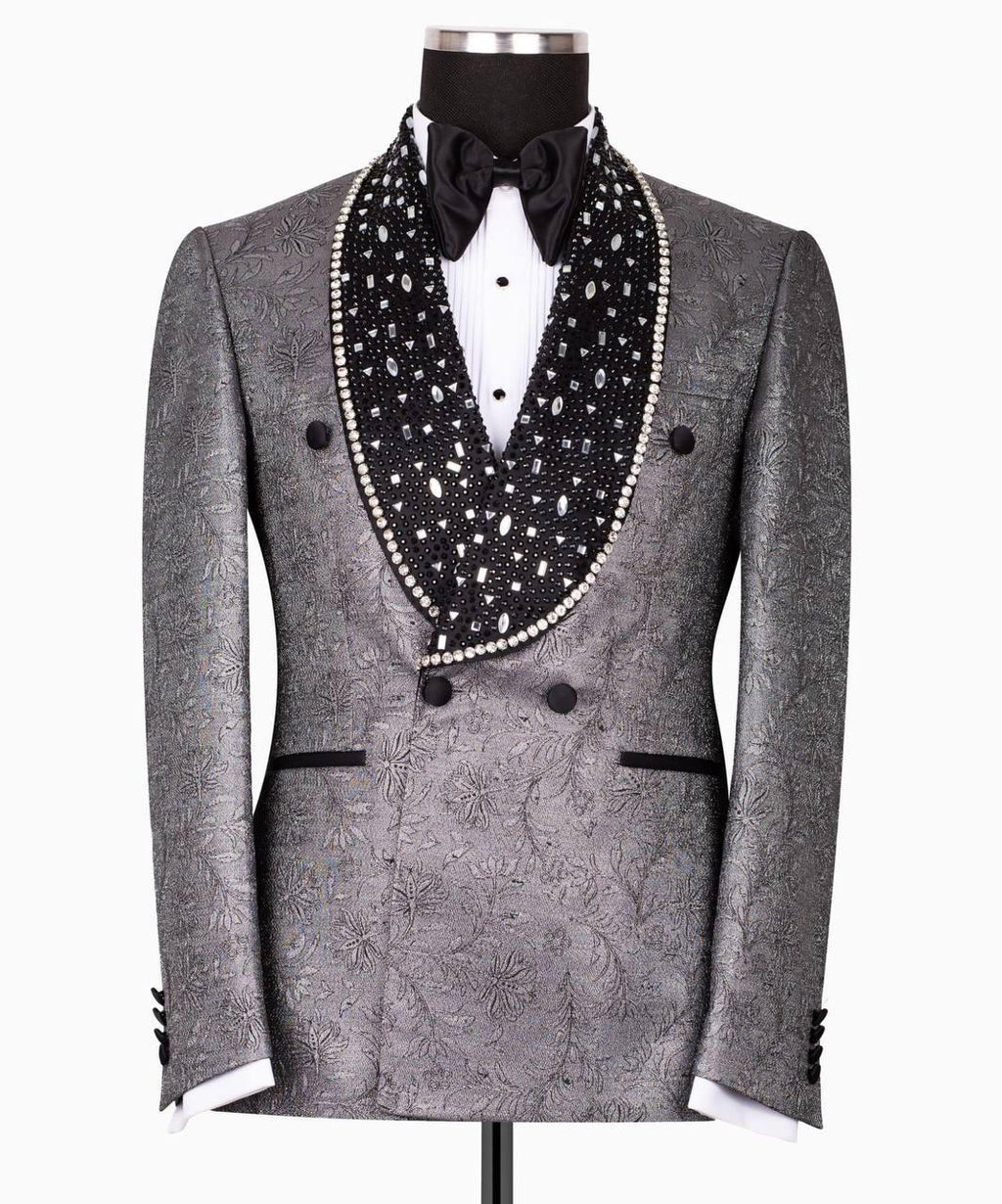 A gray patterned double-breasted tuxedo jacket displayed on a mannequin, featuring a black shawl collar embellished with white pearls and a black bow tie.