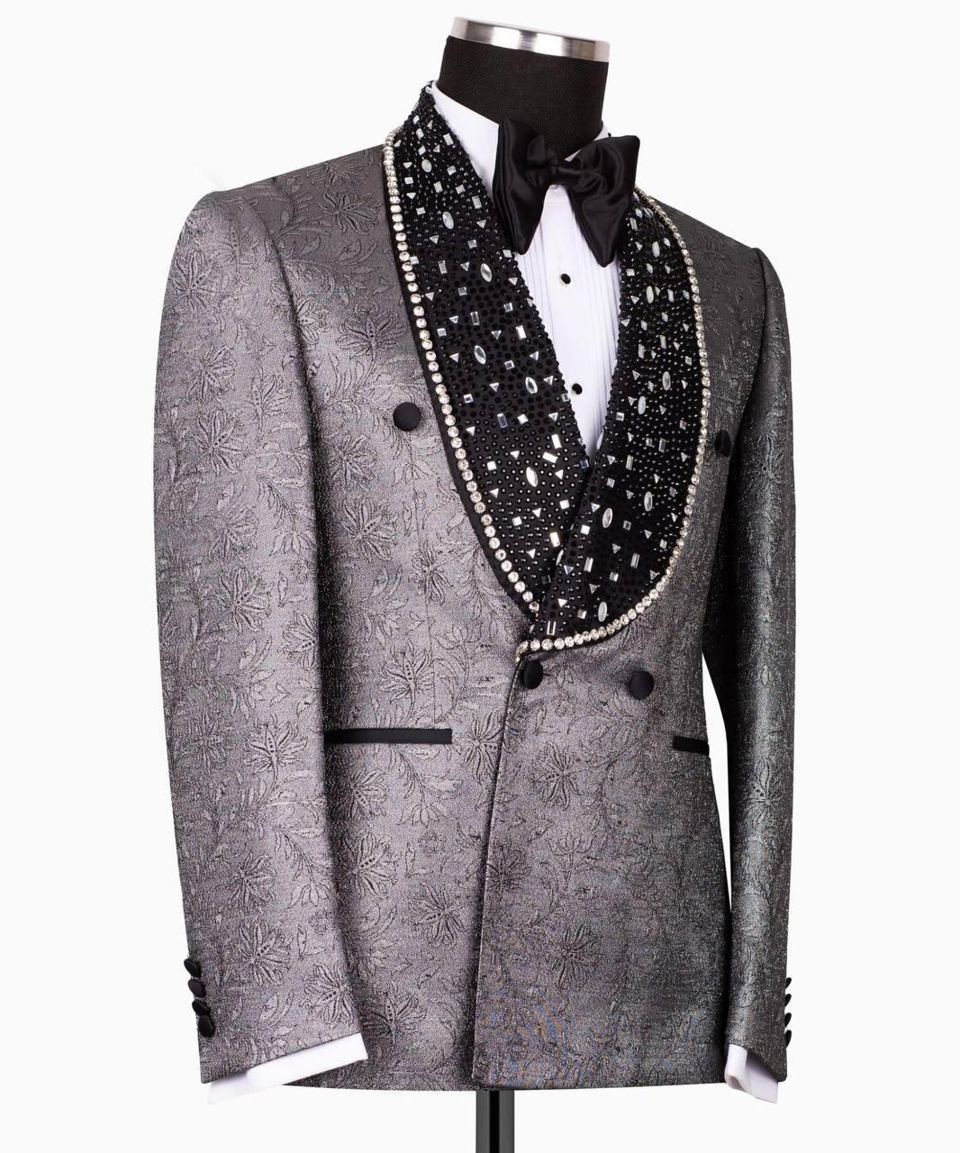 A men's tuxedo jacket displayed on a mannequin torso, featuring a textured gray and silver jacquard pattern, a black beaded shawl collar, a white dress shirt, and a black bow tie.