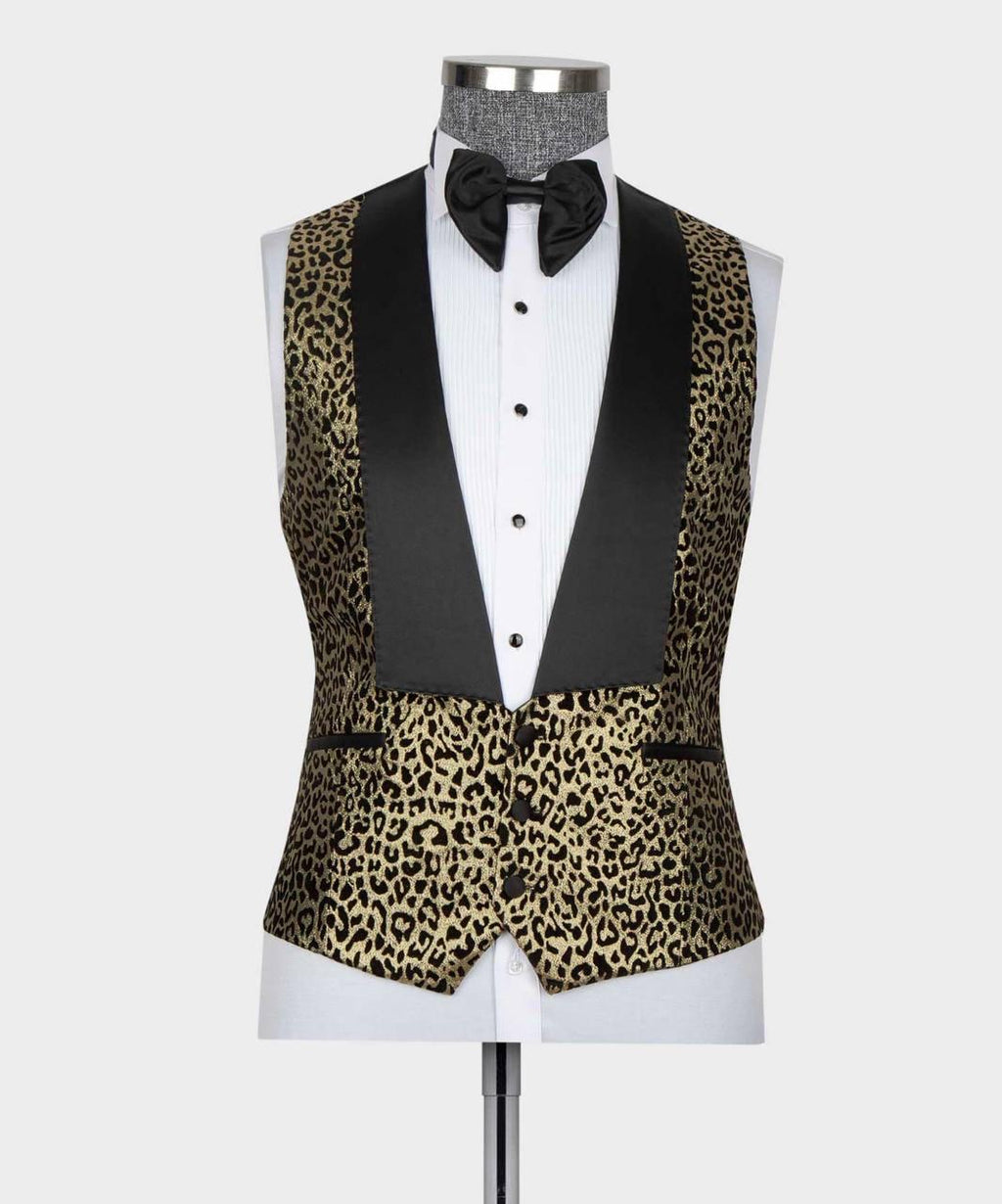 A men's tuxedo vest with a black and gold leopard print pattern and solid black satin peak lapels, displayed on a white dress shirt mannequin with a black bow tie against a light gray background.