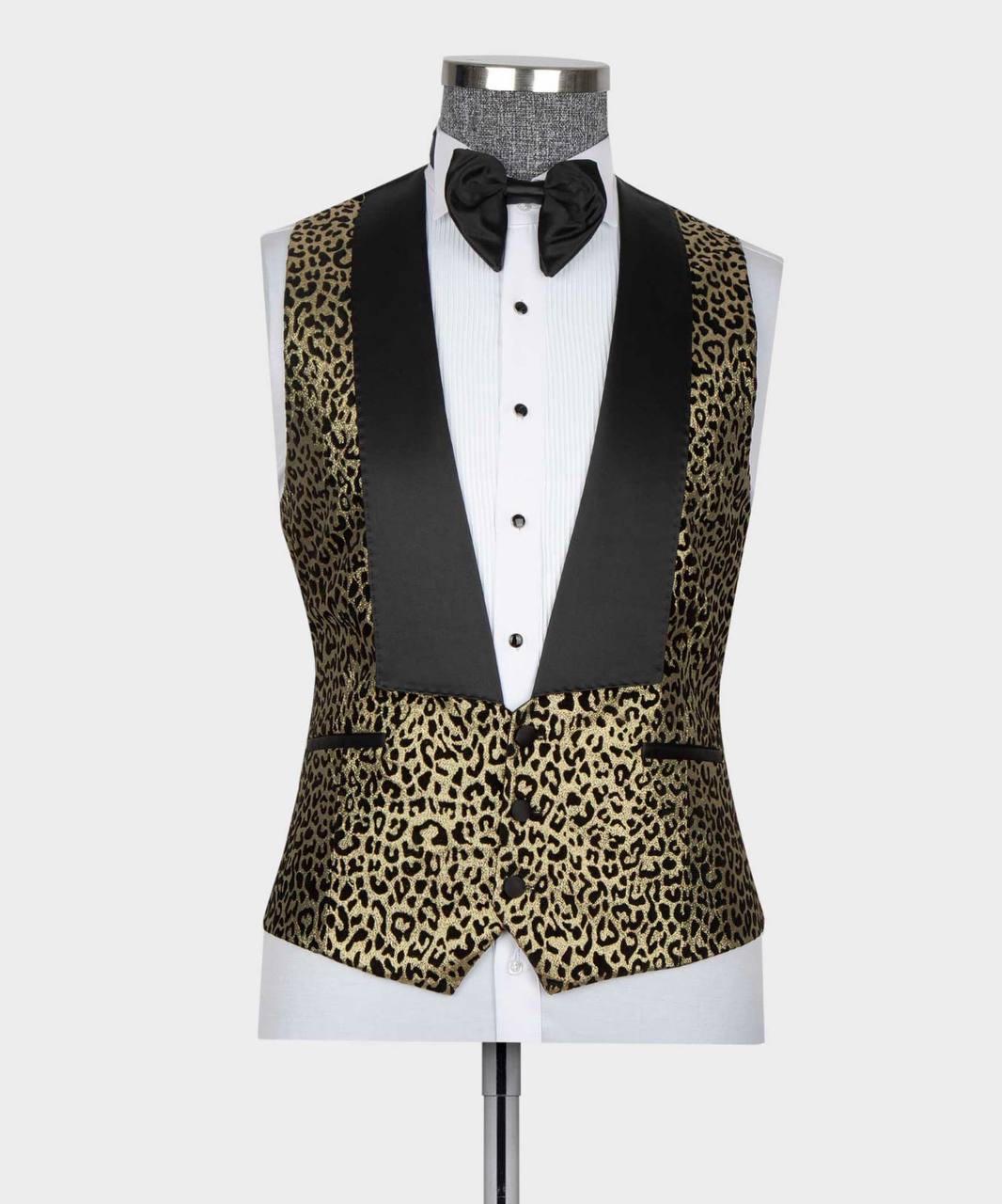 A men's tuxedo vest with a black and gold leopard print pattern and solid black satin peak lapels, displayed on a white dress shirt mannequin with a black bow tie against a light gray background.