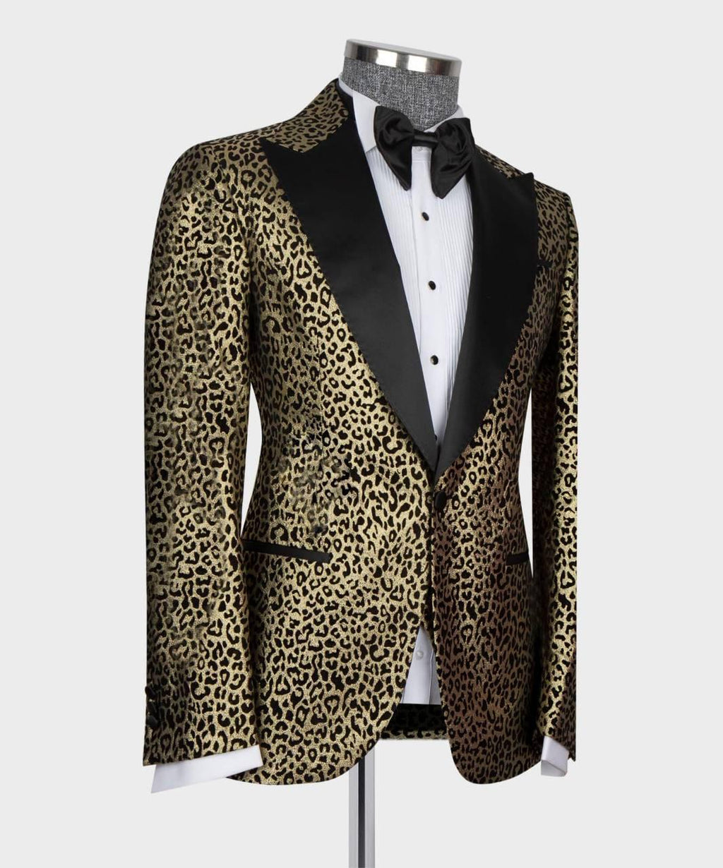 A men's tuxedo jacket with a gold and black leopard print pattern and black satin peak lapels, styled on a mannequin with a white tuxedo shirt and black bow tie against a light gray background.