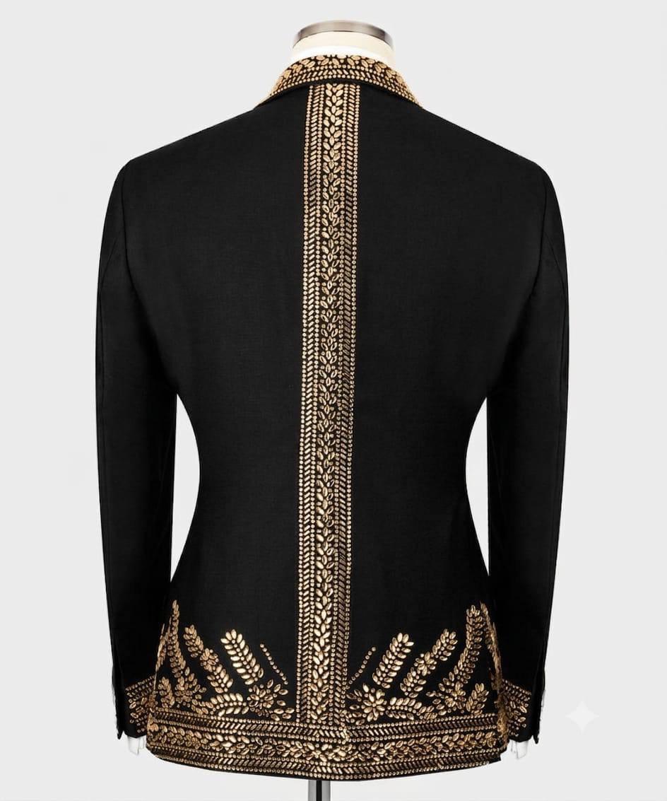 Black long-sleeve blazer shown from the back on a mannequin, featuring ornate gold embroidery running down the center back and around the hem.