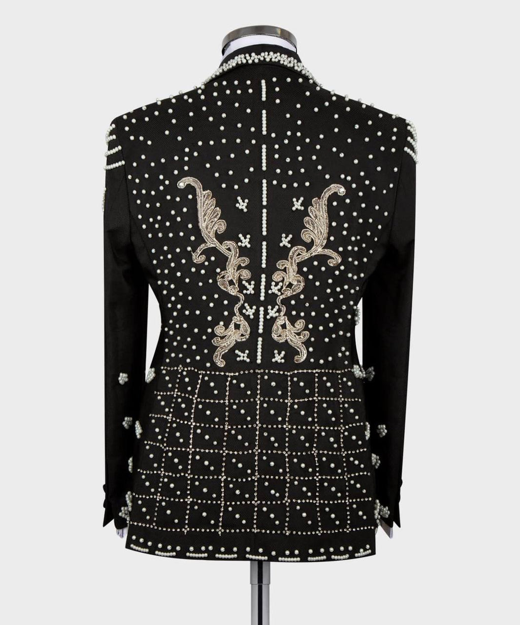 A black embellished jacket displayed on a mannequin, showing the back view with silver rhinestone studs, white embroidered scrollwork, and a white polka dot pattern on a light gray background.