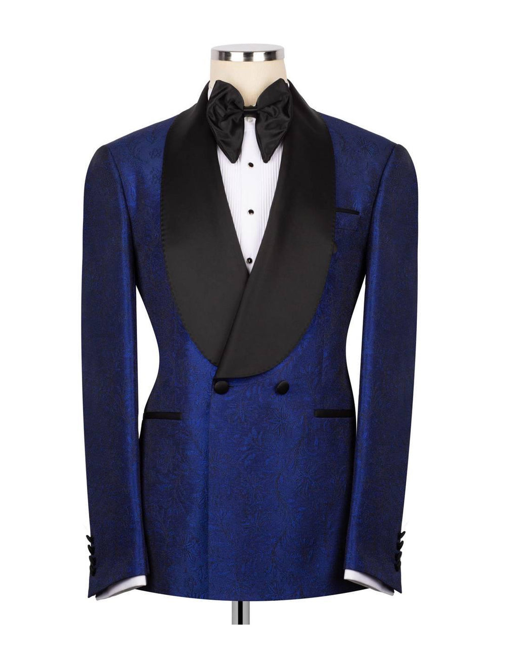 A men's tuxedo jacket displayed on a mannequin torso, featuring a rich royal blue jacquard patterned fabric body with contrasting black satin shawl lapels, a black bow tie, and a white dress shirt.