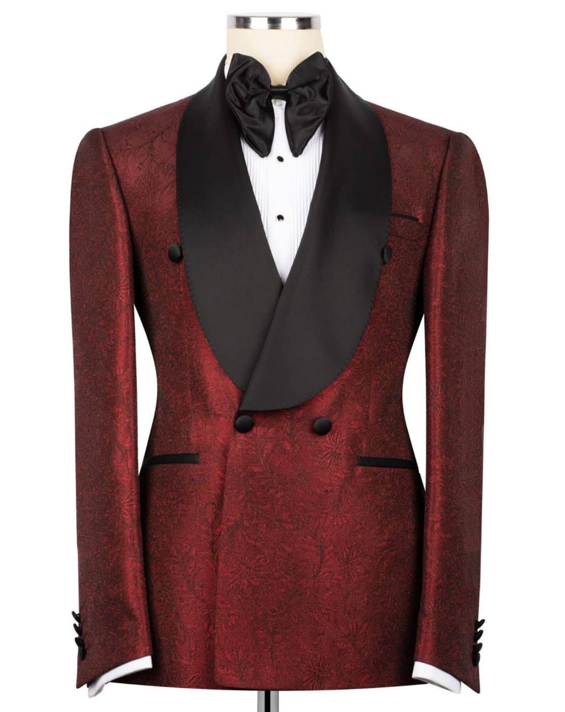 A men's double-breasted tuxedo jacket in a deep burgundy brocade fabric with contrasting black satin shawl collar, black buttons, and a black bow tie, displayed on a mannequin torso.
